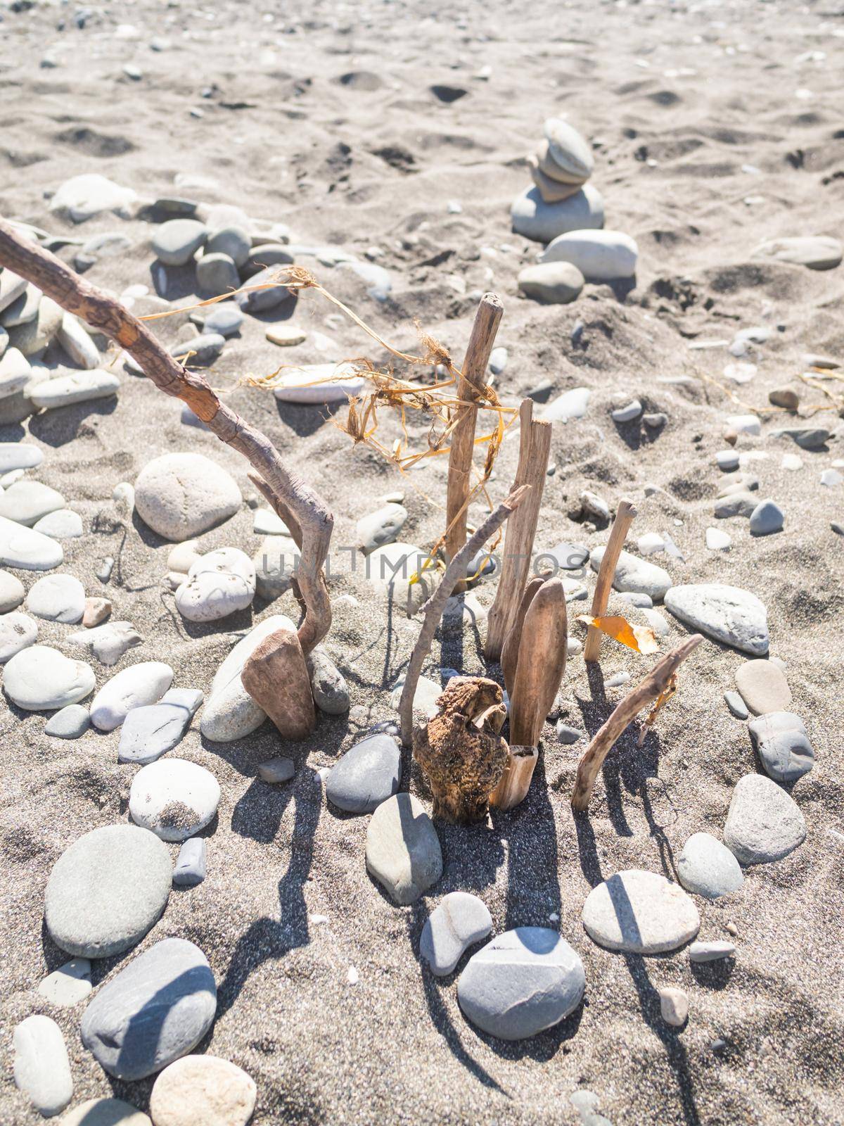 Pyramid built with stones and driftwood on pebble beach. Vacation on seaside. Exploring nature in childhood.