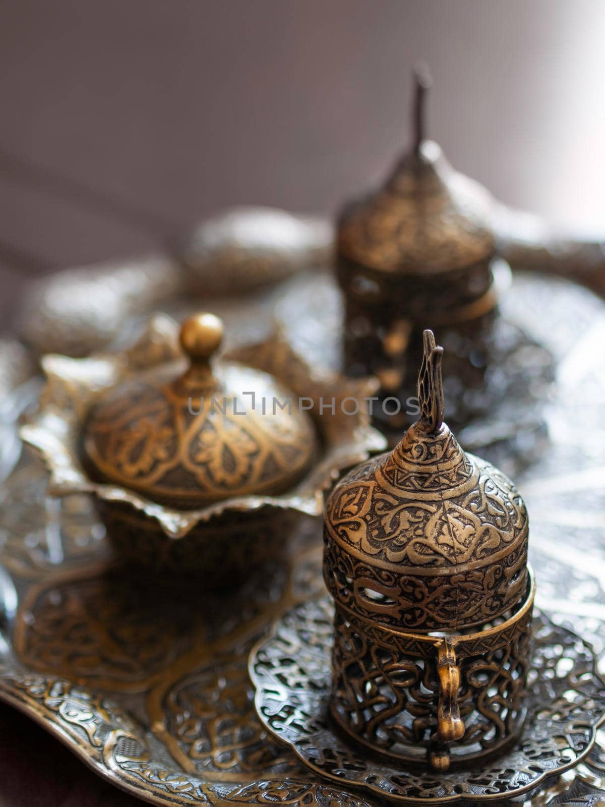 Metal tea set with eastern ornament. Graceful dishes and utensils on tray.