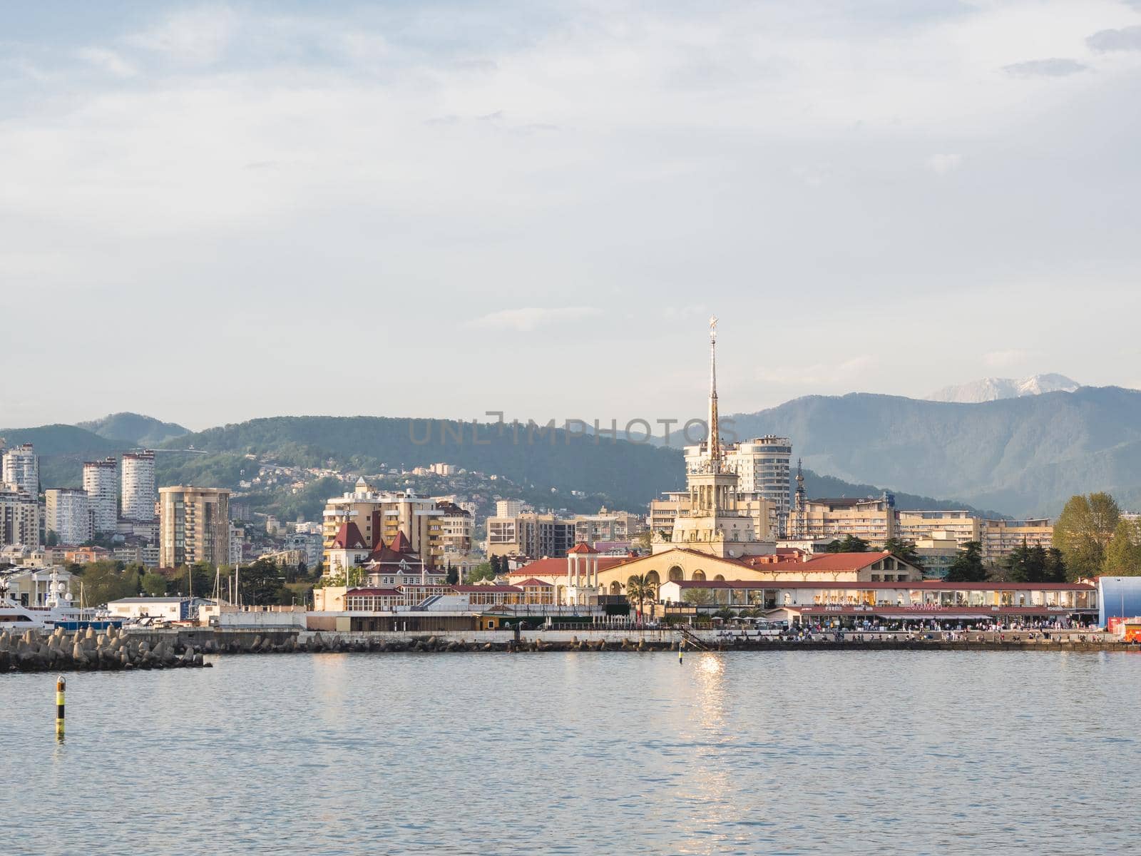SOCHI, RUSSIA - May 03, 2021. Port of Sochi, sea embankment and residential district at sunset. View from Black sea in sunny weather.