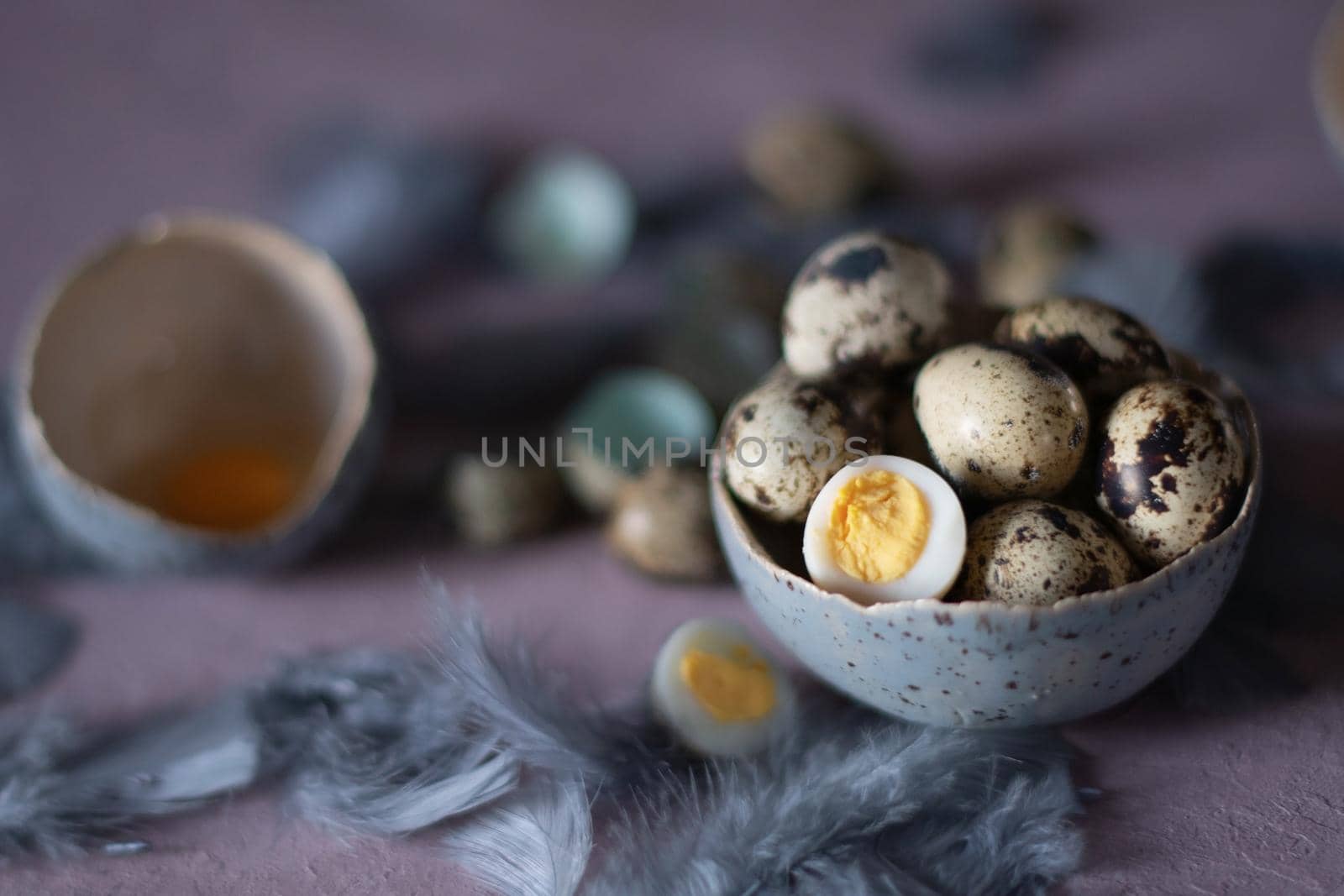 quail eggs in ceramic vases, gray feathers on the table, easter still life, natural food, diet and antioxidants, dark key and shallow depth of field. High quality photo