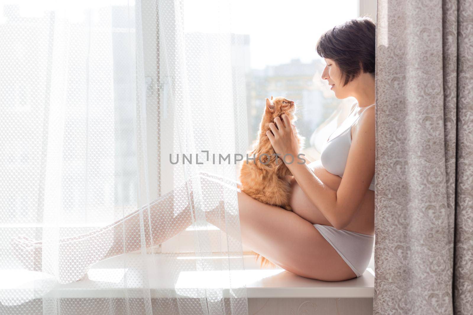 Pregnant woman in white underwear with cute ginger cat. Young woman expecting a baby. Risk of infection toxoplasmosis. by aksenovko