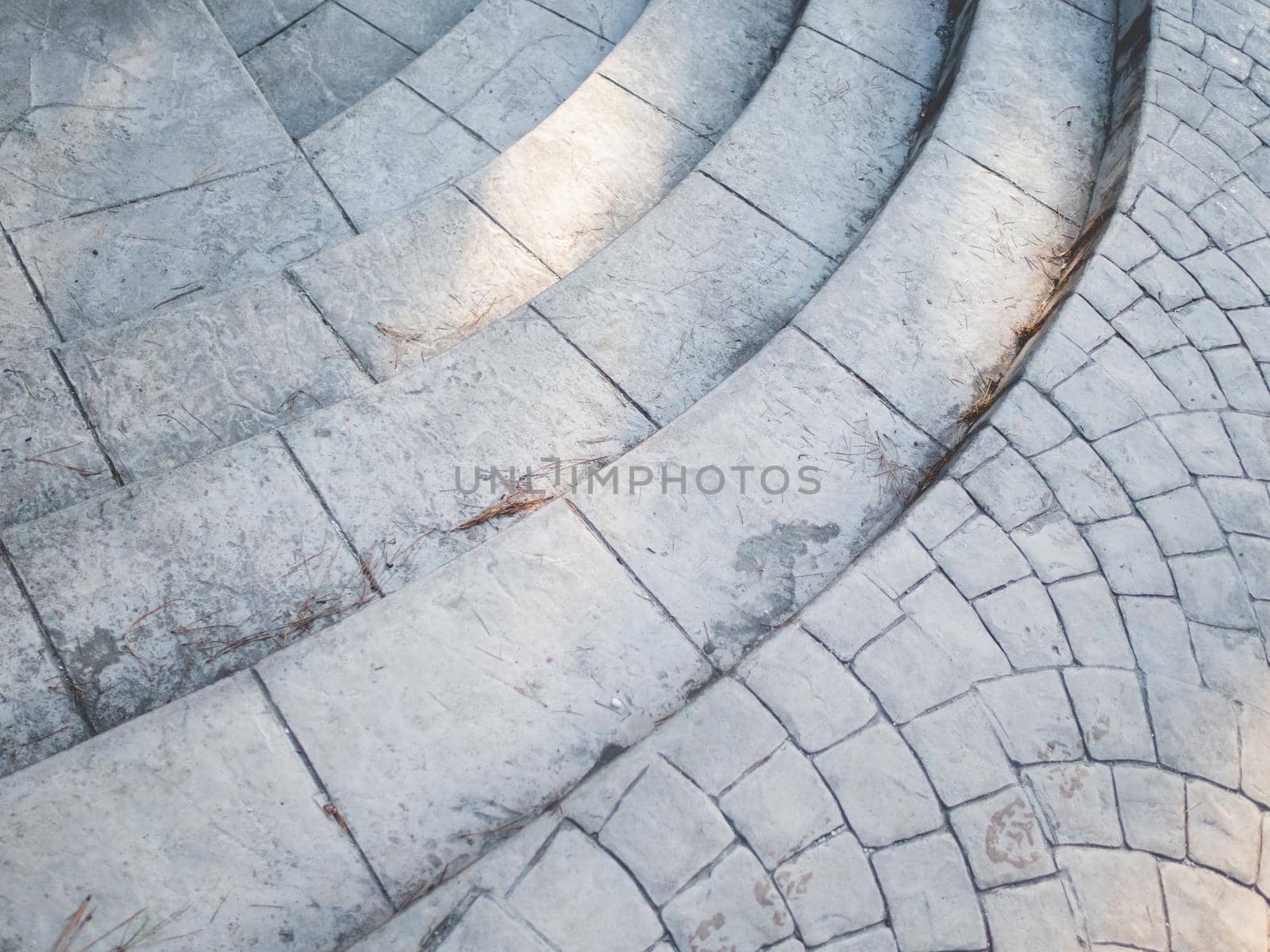 Exterior of grey tiled staircase. Sunlight and shadow on stone curved steps. Urban geometry.