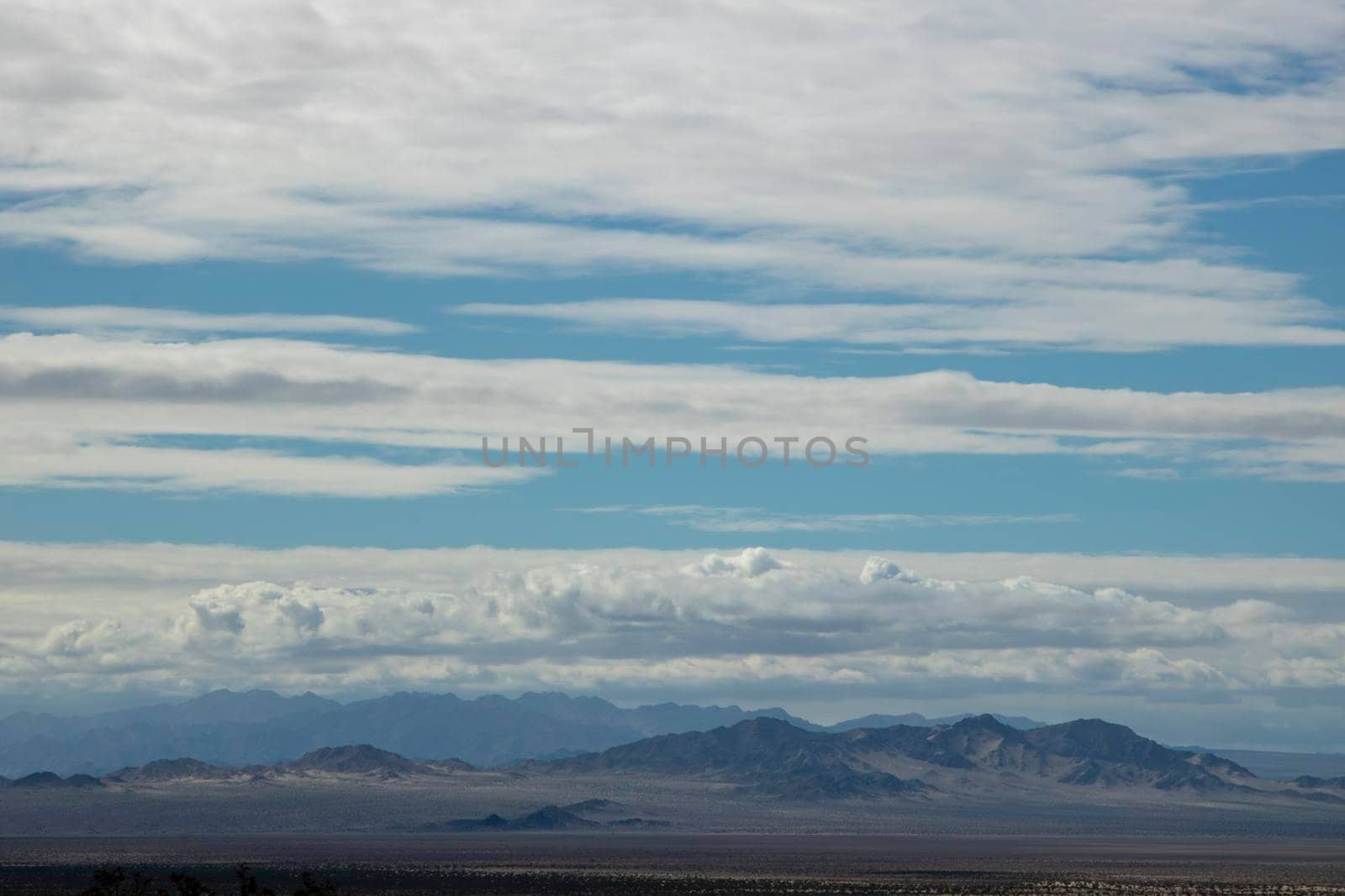 Desert view and some mountains under a cloudy sky