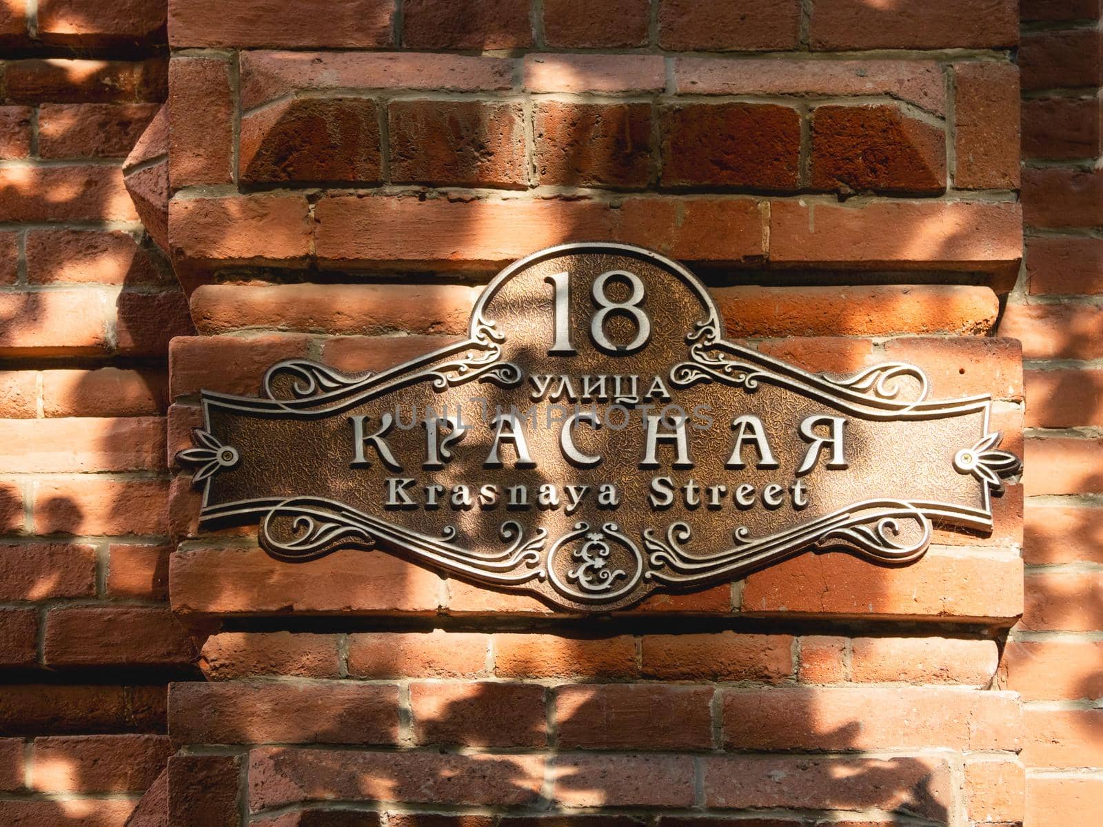 KRASNODAR, RUSSIA - June 02, 2021. Old fashioned sign of Krasnaya street. Sunlight on red brick wall and vintage street pointer.