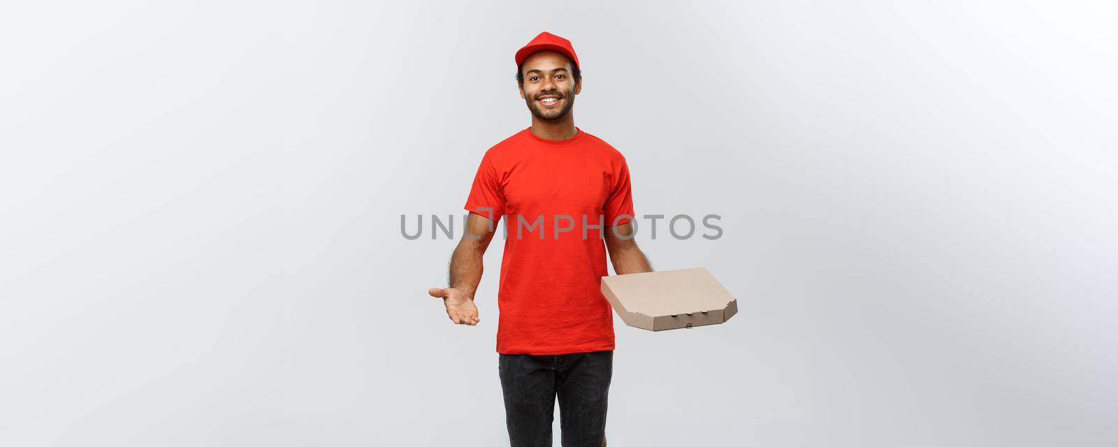 Delivery Concept - Portrait of Happy African American delivery man pointing hand to present a pizza box package. Isolated on Grey studio Background. Copy Space