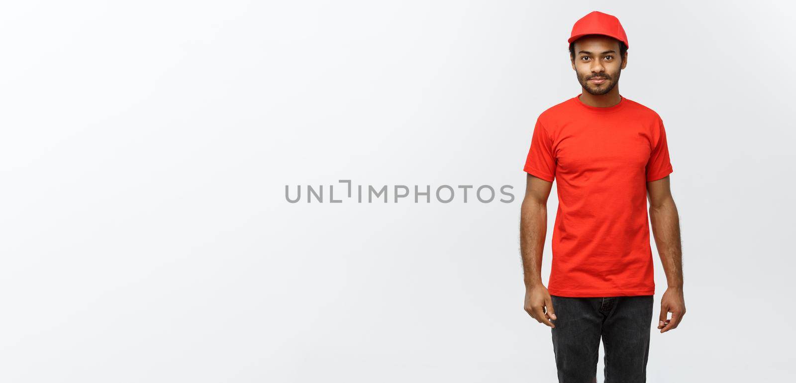 Delivery Concept - Handsome African American delivery man. Isolated on Grey studio Background. Copy Space. by Benzoix