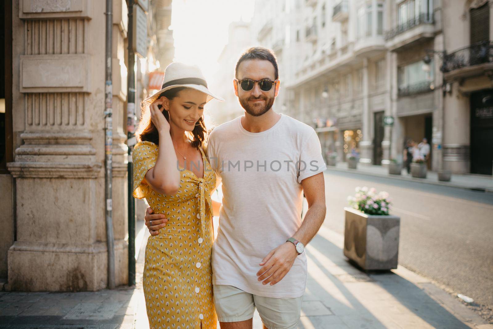 A man with a beard is hugging around the waist of a girlfriend on the sunset. by RomanJRoyce