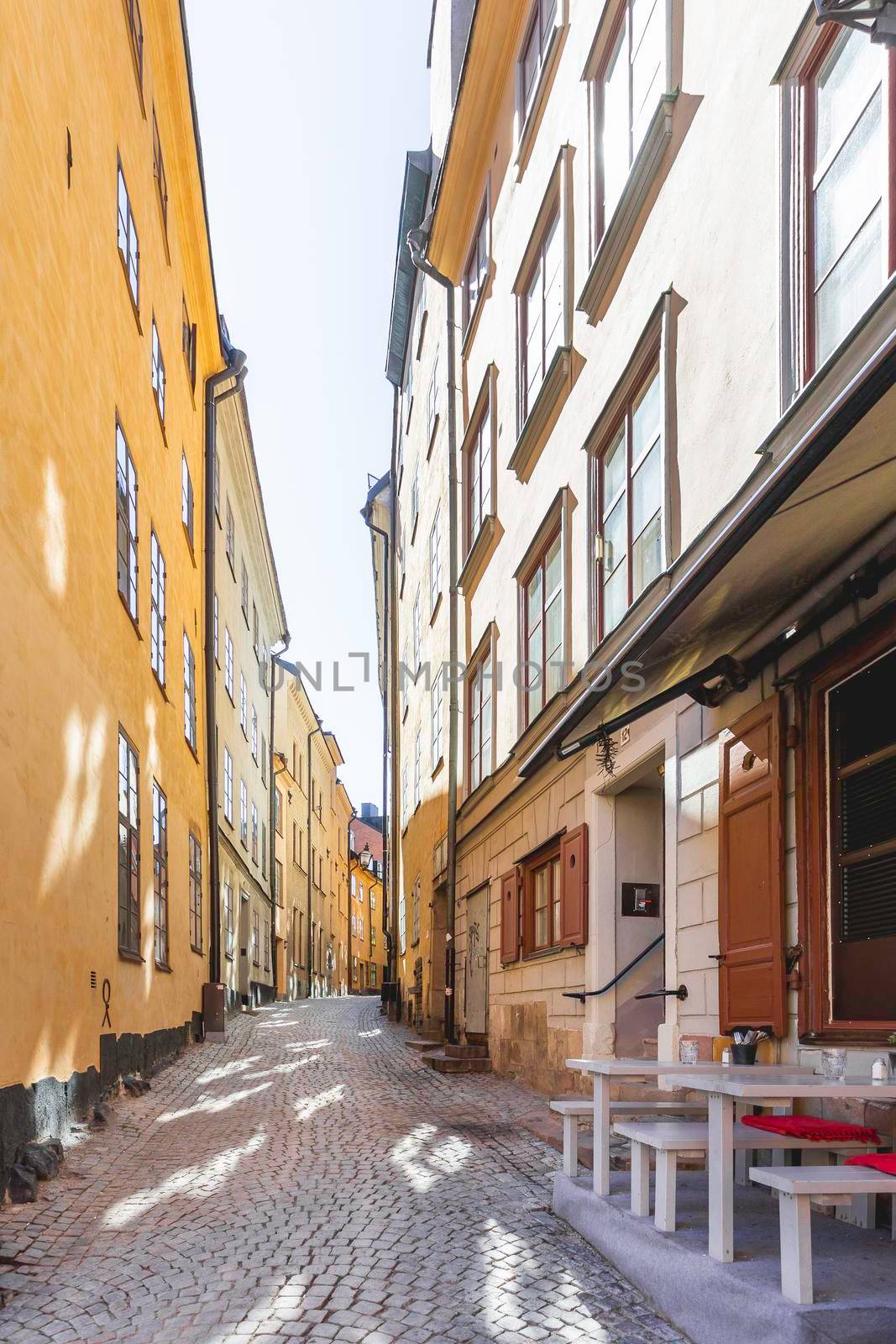 STOCKHOLM, SWEDEN - July 06, 2017. Bright sun reflections on narrow street in historic part of Stockholm. Old fashioned building in Gamla stan, old part of town. by aksenovko