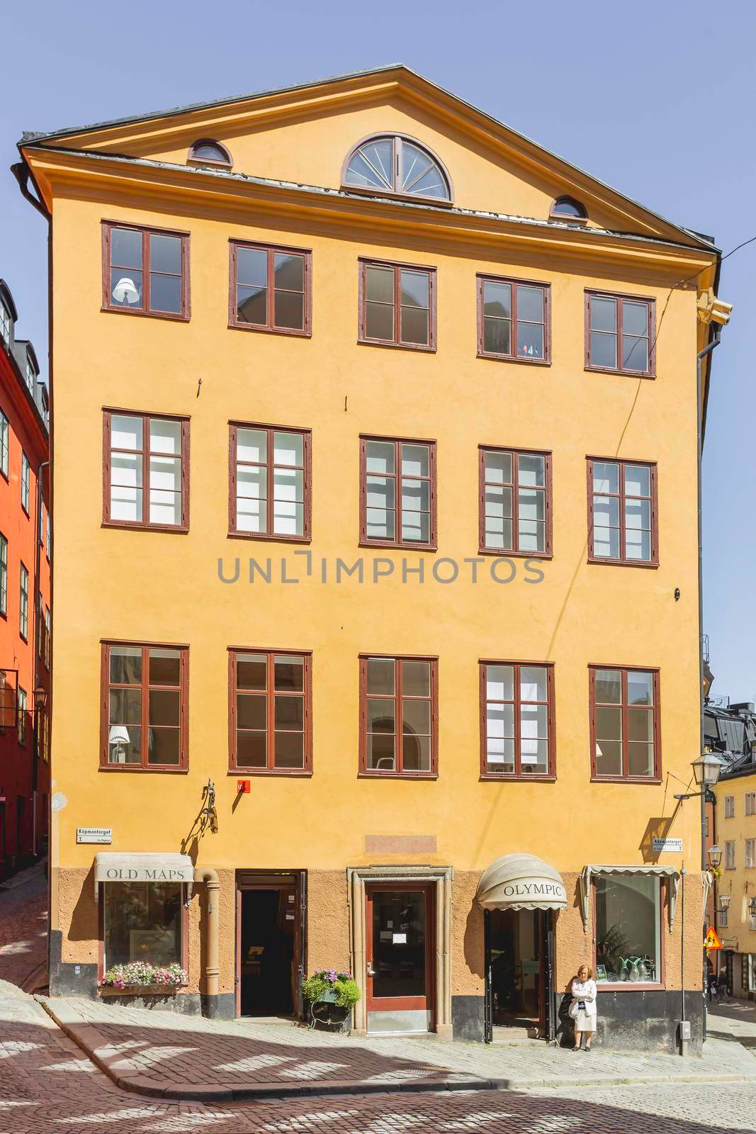 STOCKHOLM, SWEDEN - July 06, 2017. Shop with old maps with open doors. Sun reflections on bright yellow walls in Gamla stan. Colorful old fashioned buildings in historical part of town. by aksenovko
