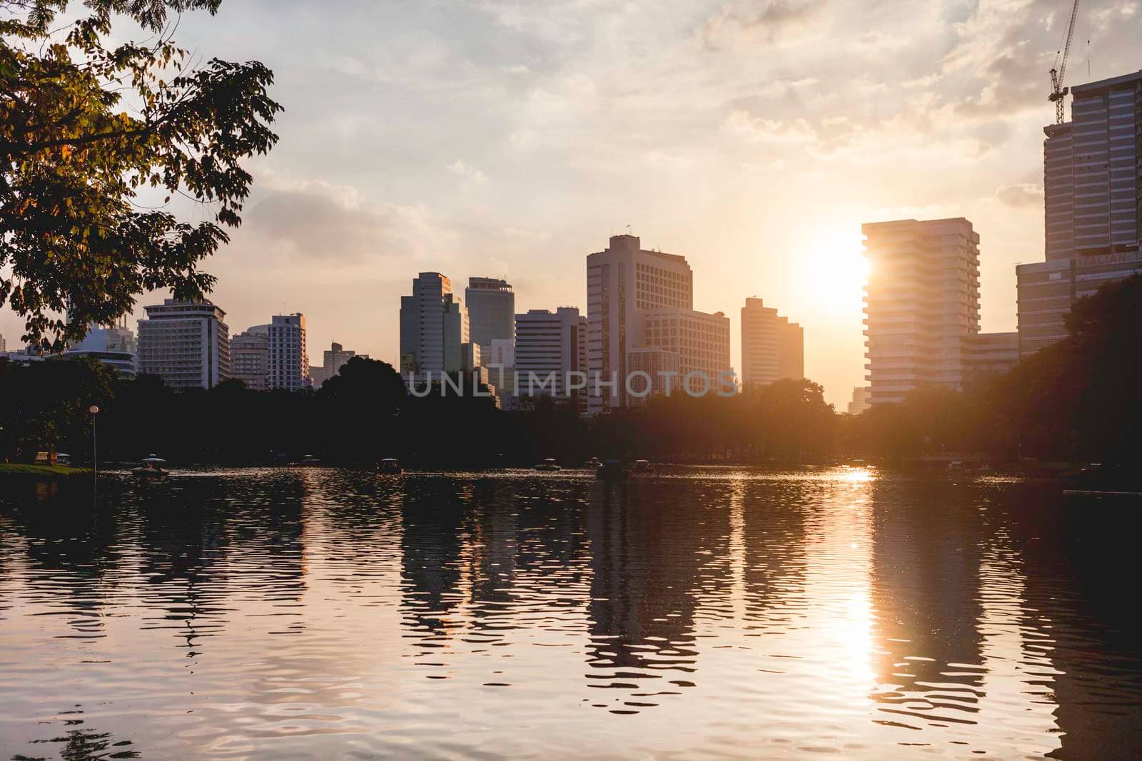BANGKOK, THAILAND - October 22, 2012. Panorama of downtown skyscrapers from Lumpini park. Sunset view over pond in recreation park.