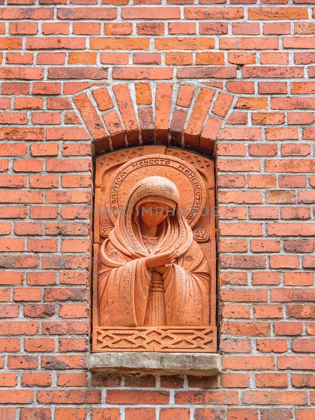 SVETLOGORSK, RUSSIA - July 21, 2019. Statue of Madonna in red brick wall near entrance of orthodox Church of Seraphim of Sarov in old building of lutheran kirk. by aksenovko