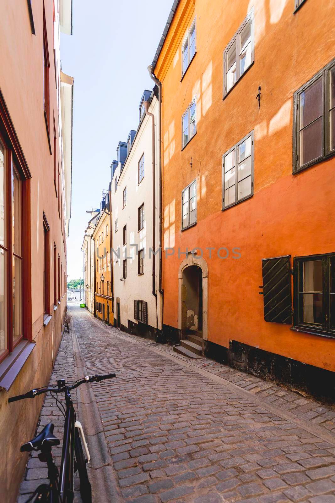 Bright sun reflections on narrow street in historic part of Stockholm. Old fashioned building in Gamla stan. Sweden. by aksenovko