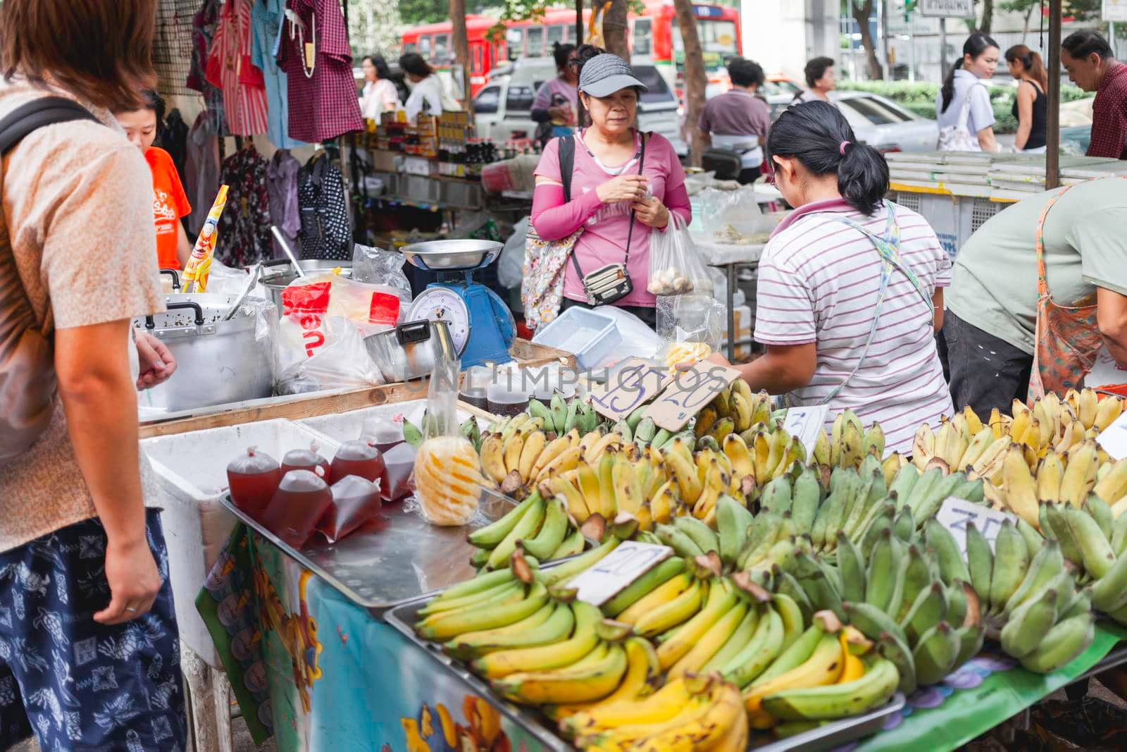 BANGKOK, THAILAND - October 23, 2012. Local people and tourists buy food on street market. Fruits and ready-to-eat soups and sauces in plastic bags.