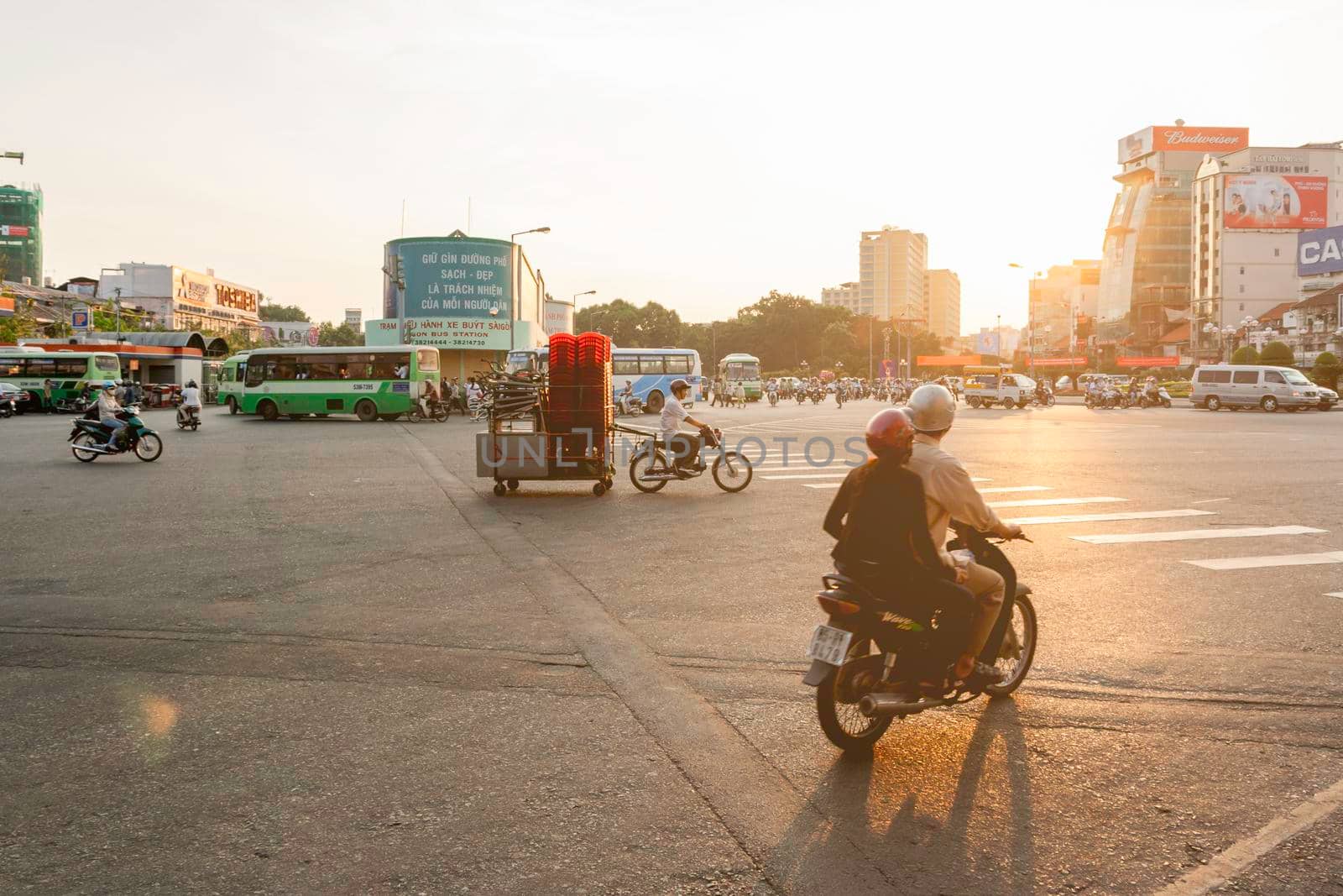 HO CHI MINH, VIETNAM - March 28, 2009. Man drives motorbike with tables and stools on trailer down the street of capital city at sunset.