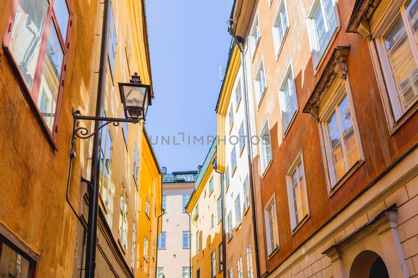 Bright sun reflections on narrow street in historical part of Stockholm. Old fashioned building in Gamla stan, old part of Stockholm, Sweden. by aksenovko
