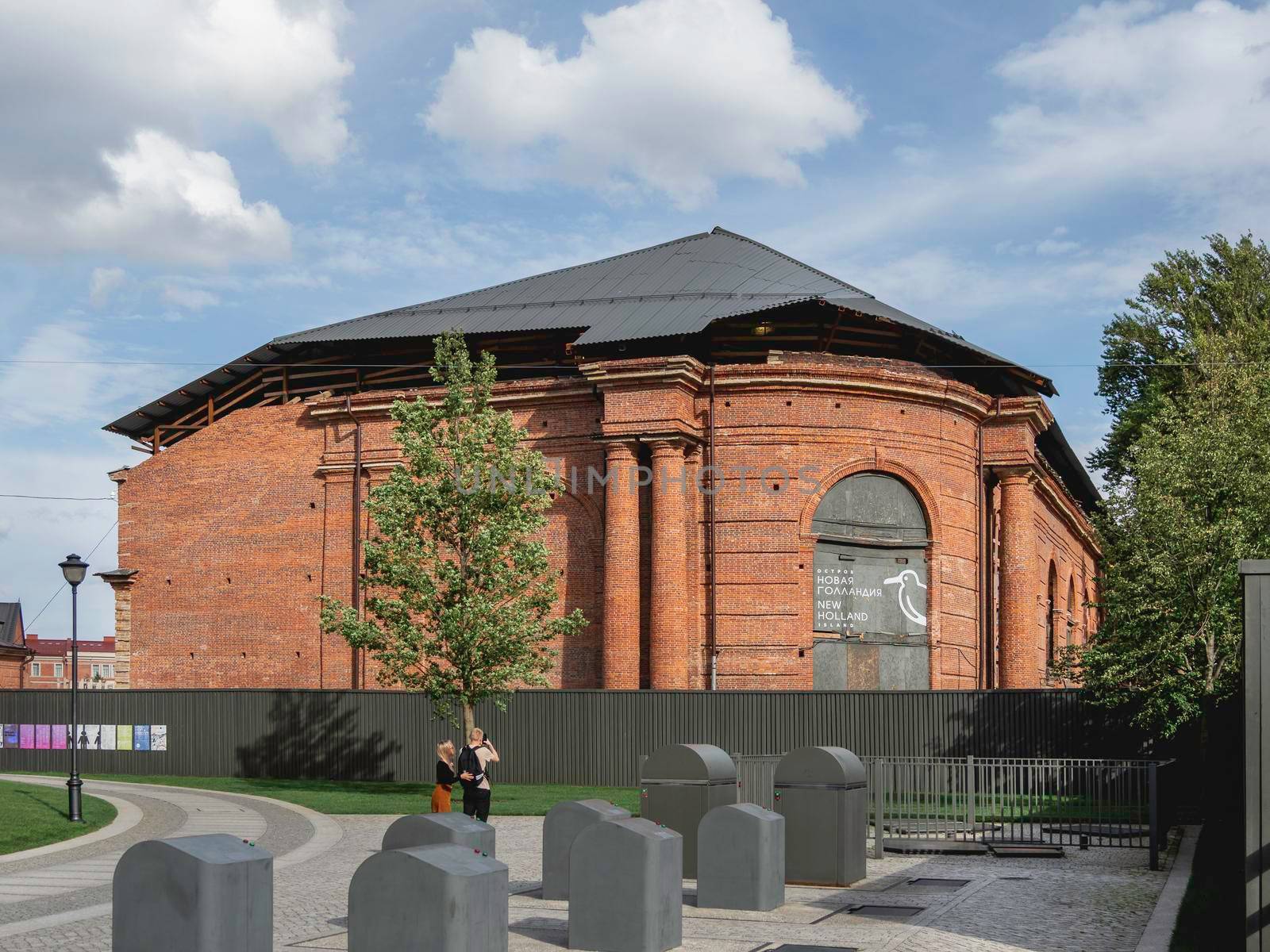 SAINT-PETERSBURG, RUSSIA - August 15, 2021. Tourists take pictures of o red brick buildings in New Holland - modern recreation park in historical center of town.