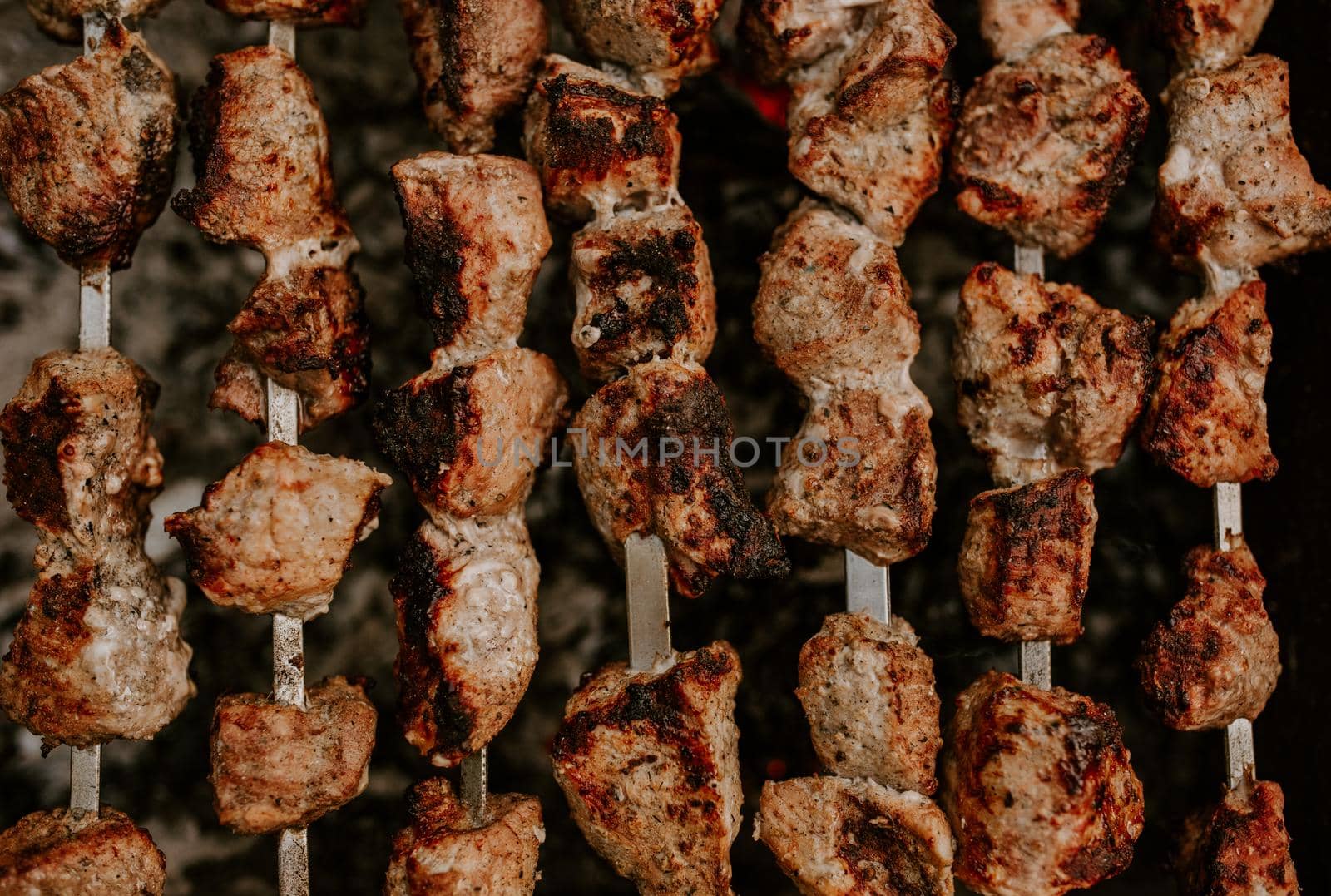 Pork veal cow meat cut into square pieces and fried over a fire. A lot of meat on skewers lies side by side in parallel, one to one.