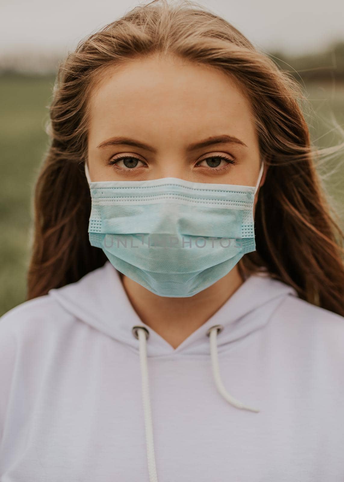 Young blond European woman in a protective mask outdoors.