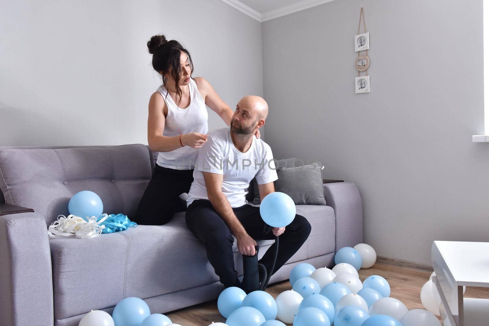 Family couple blowing white and blue balloons. Man and woman preparing before party