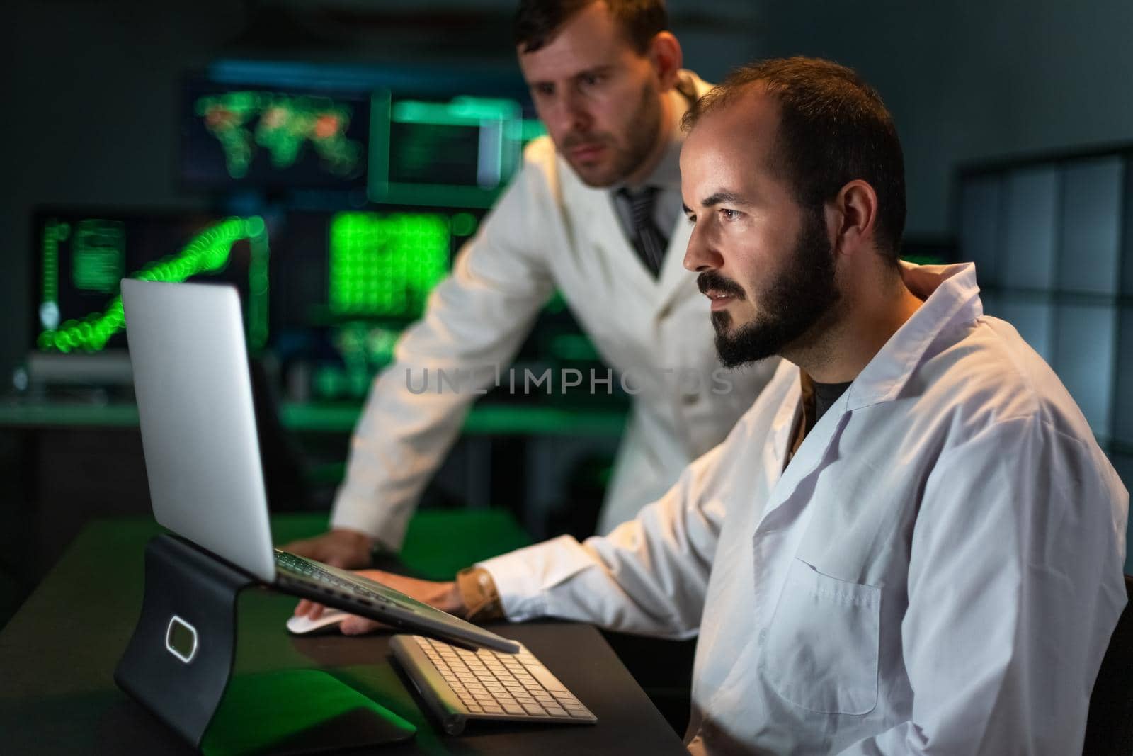 Two male doctor colleagues analyze some experiment results in the laptop. Working in laboratory. Science and technology concept.
