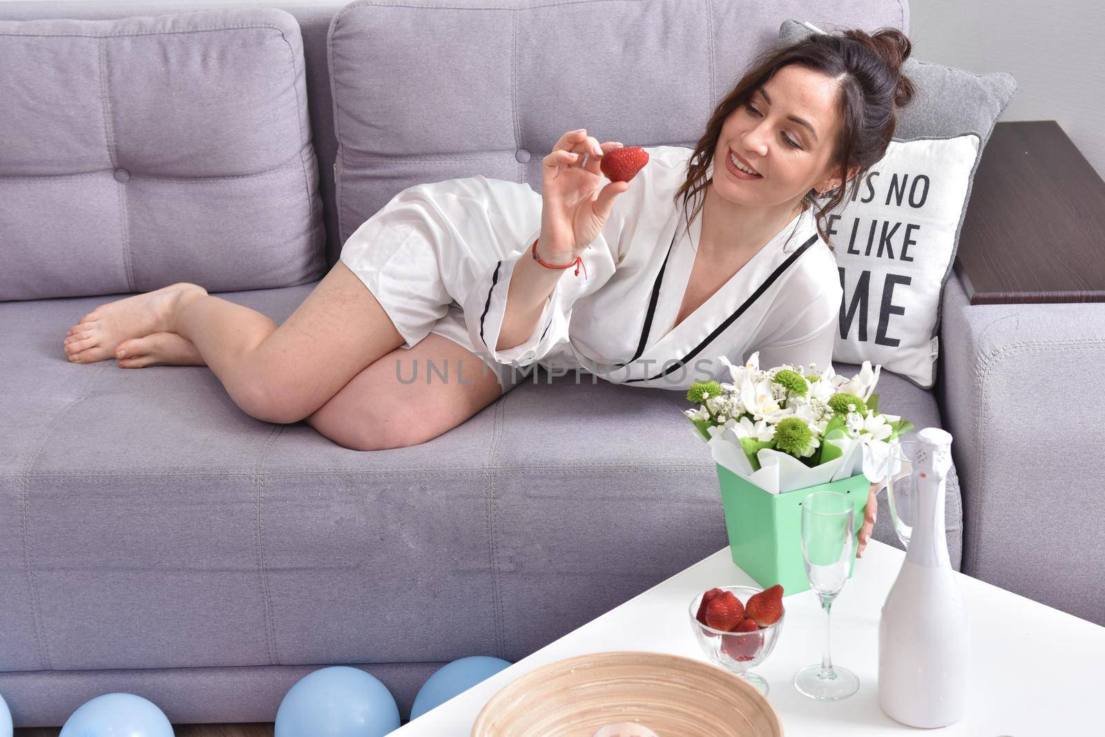 Beautiful brunette woman dressing gown with bouquet indoors. Female portrait in living room