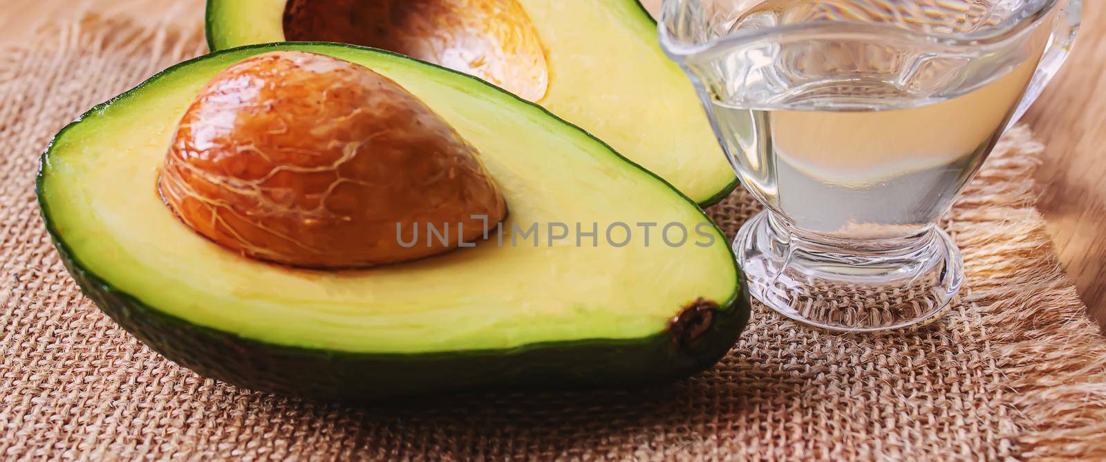 Avocado and avocado oil on wooden background. Selective focus. by mila1784