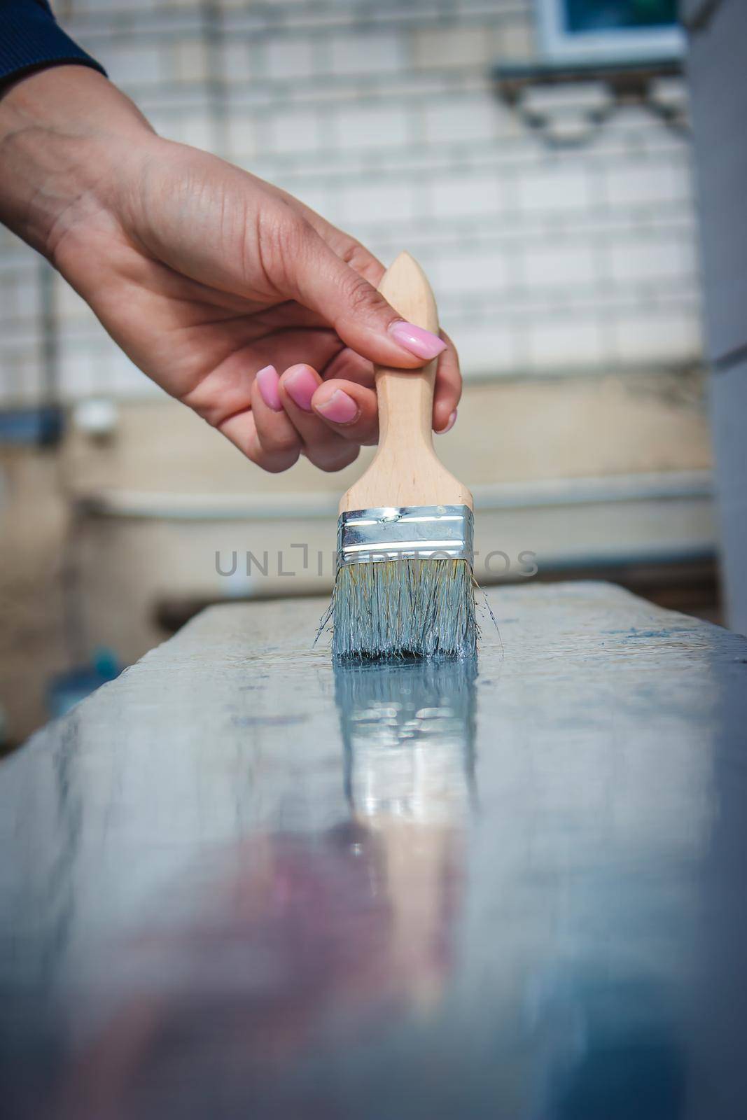 girl paints a board with a brush. Paint with gray paint. selective focus