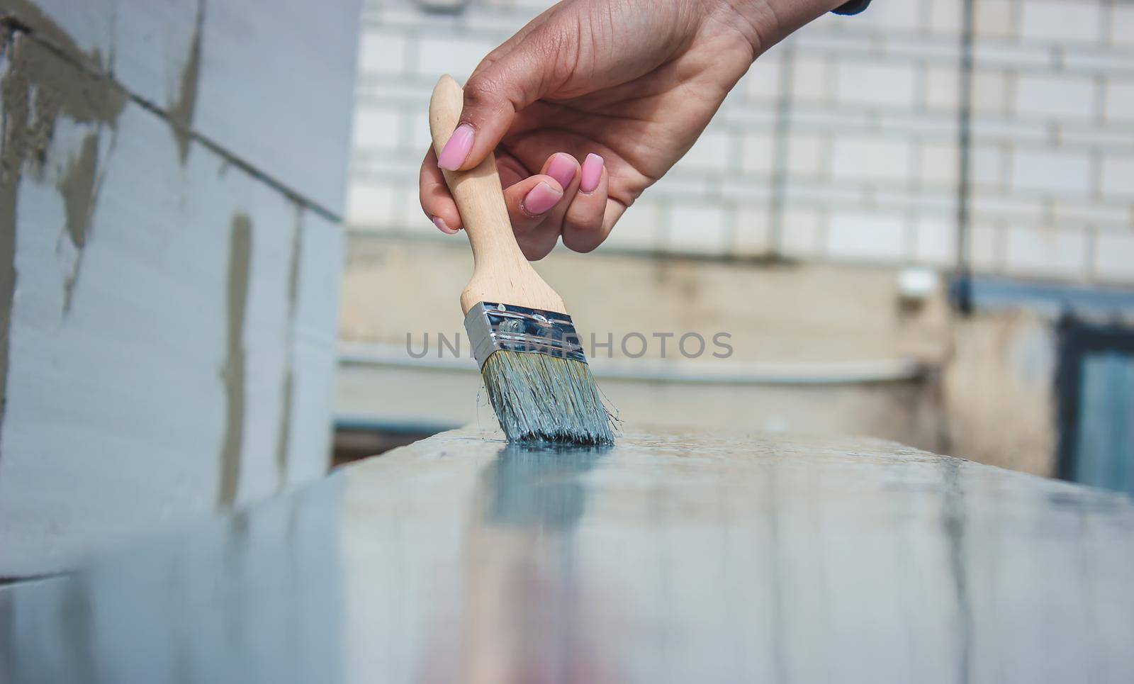 girl paints a board with a brush. Paint with gray paint. selective focus