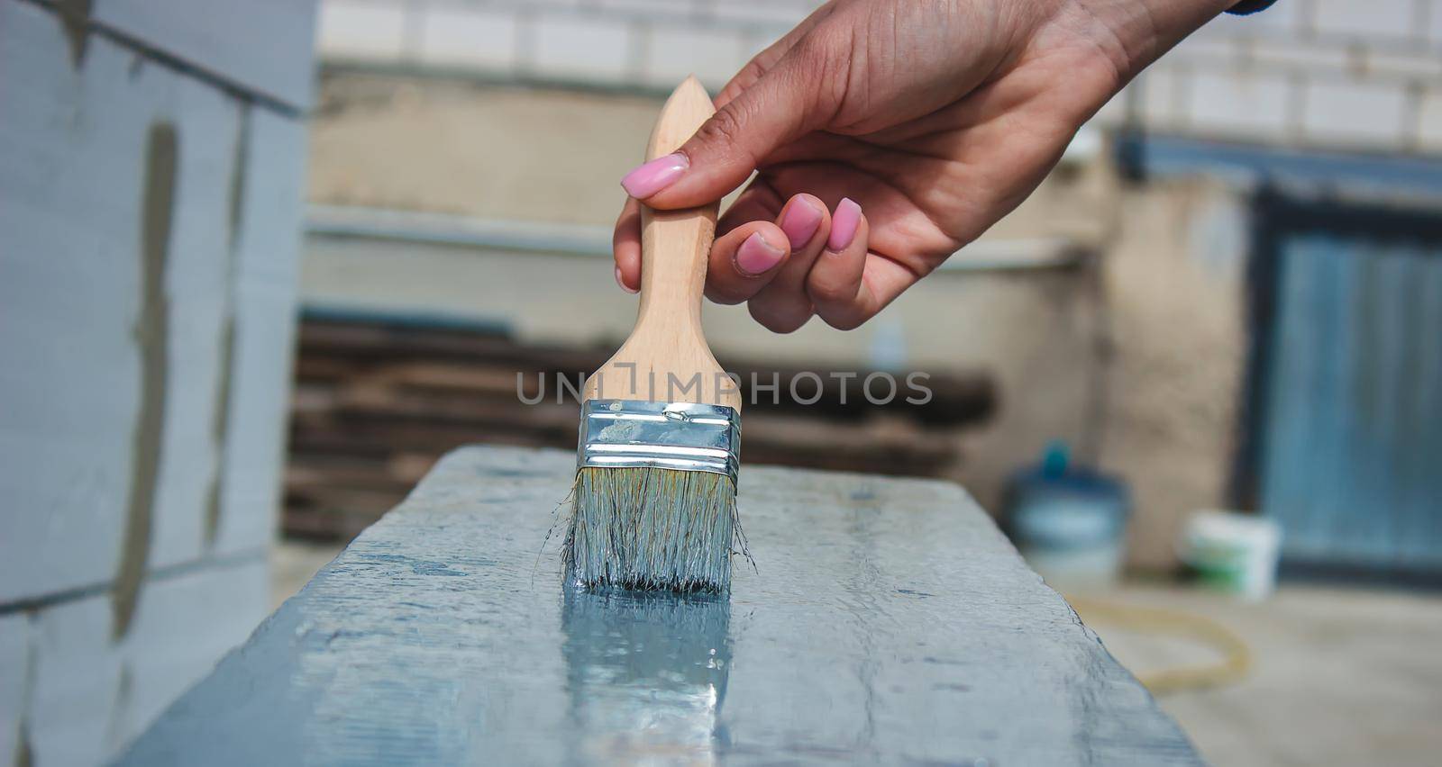 girl paints a board with a brush. Paint with gray paint. selective focus