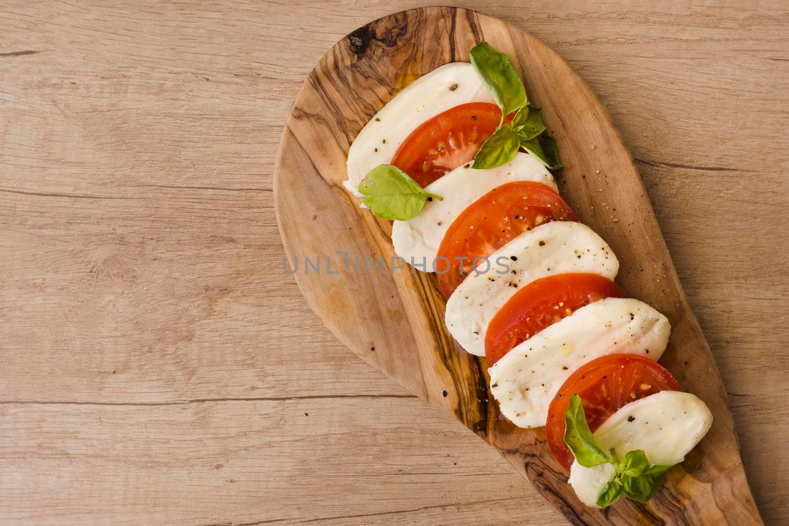 overhead view italian caprese salad with slices mozzarella cheese basil tomatoes serving board by Zahard