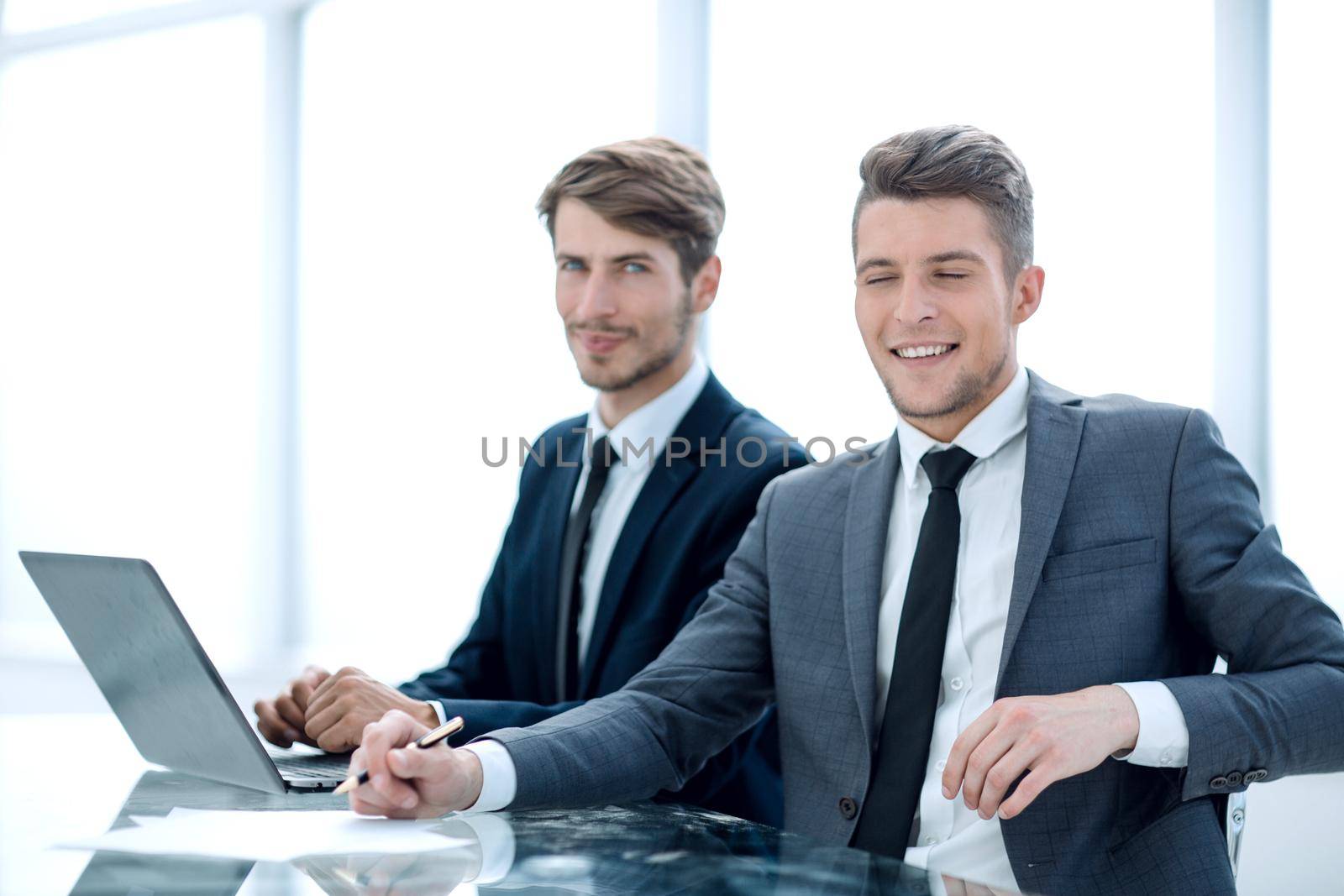 Smiling businessman and businesswoman sitting at meeting table, partners starting negotiations teamwork, satisfied entrepreneurs
