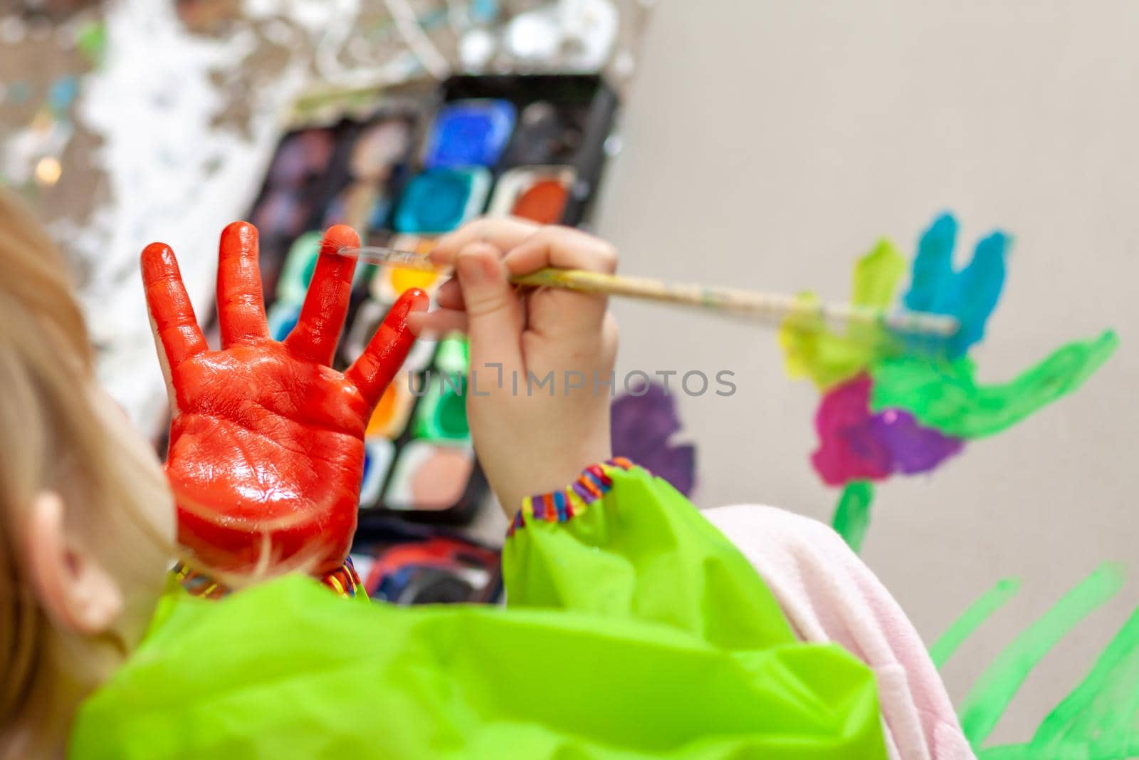 Little girl using watercolour on her own hand at home during the pandemic lockdown.