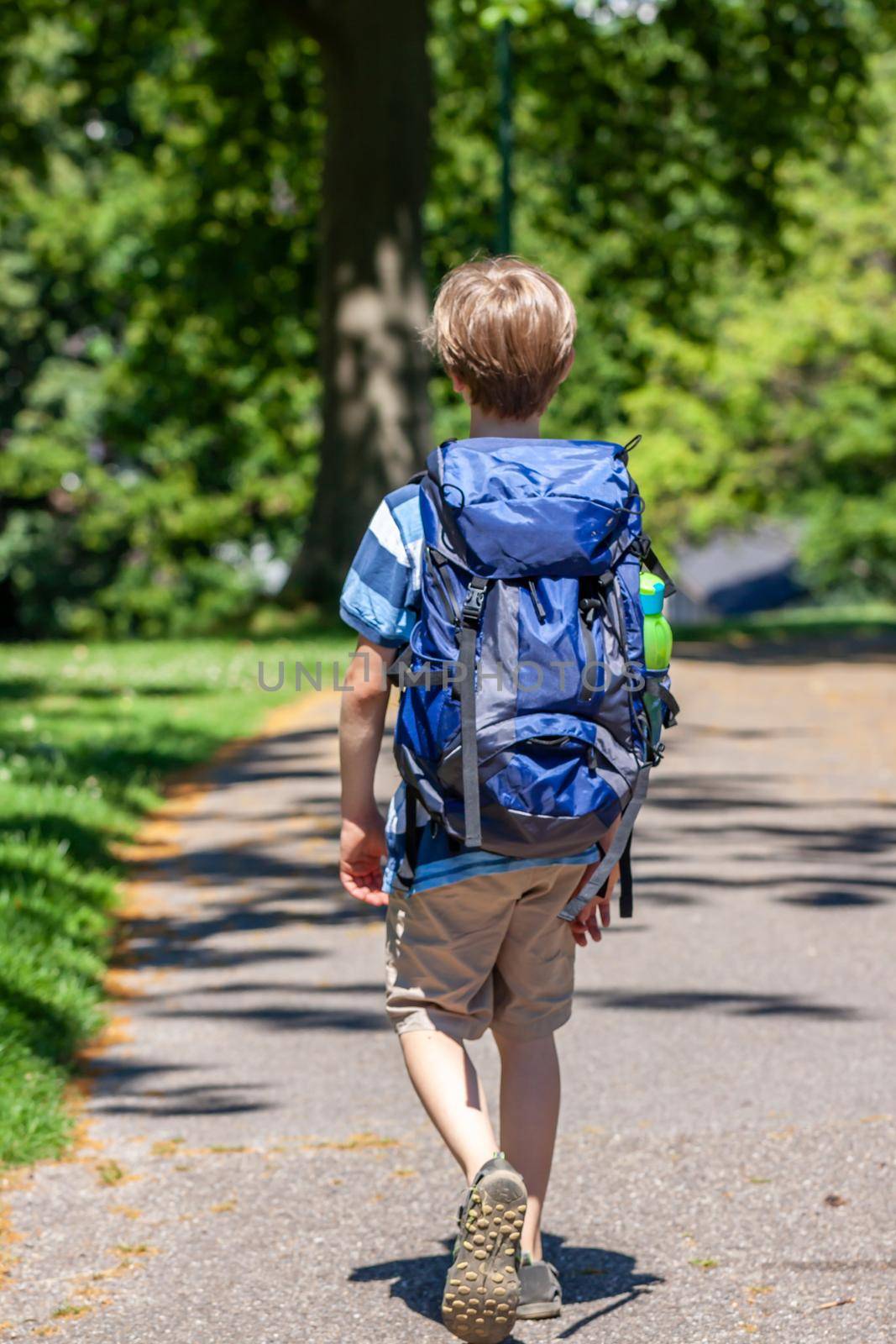 Boy hiking in the park with huge rucksack.