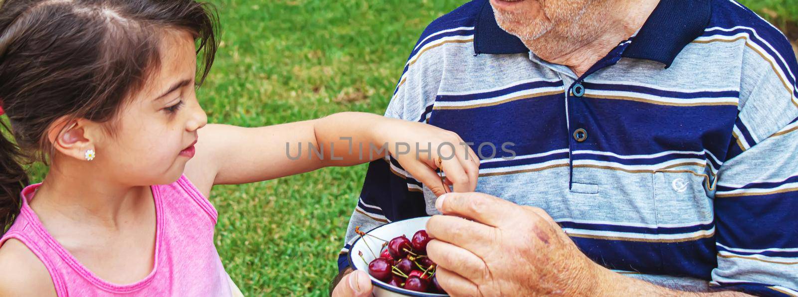 grandparents feed the child with cherries.selective focus. by mila1784