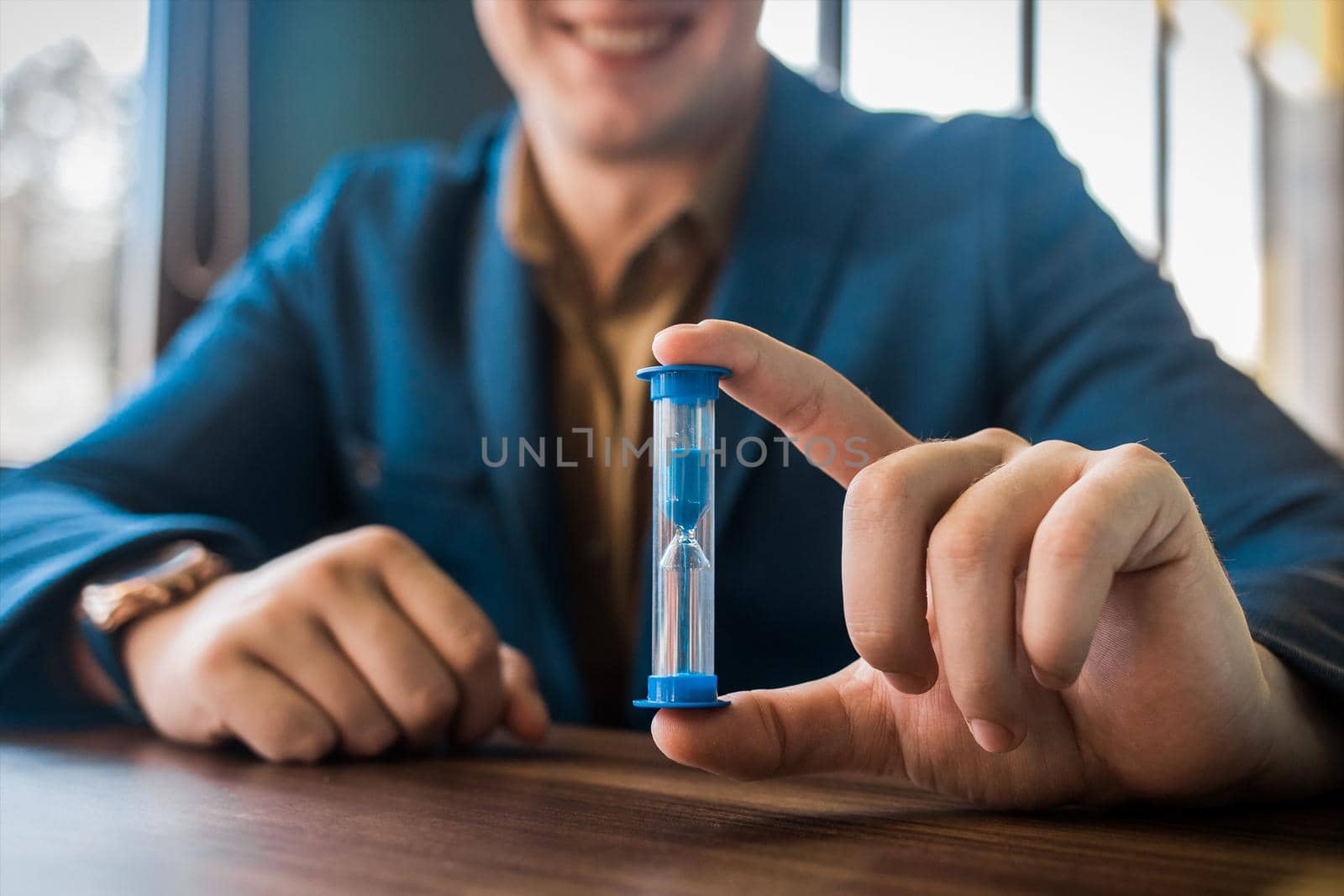 Businessman's hand holds hourglass clock timer, close-up.