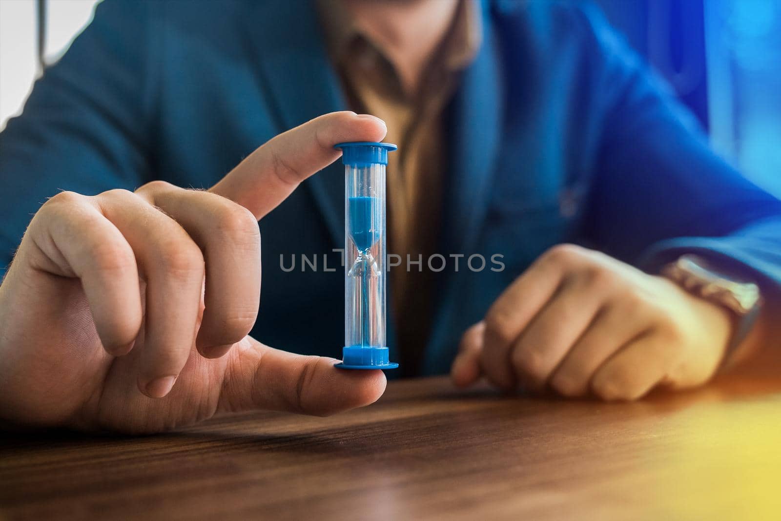 Businessman's hand holds hourglass clock timer, close-up.