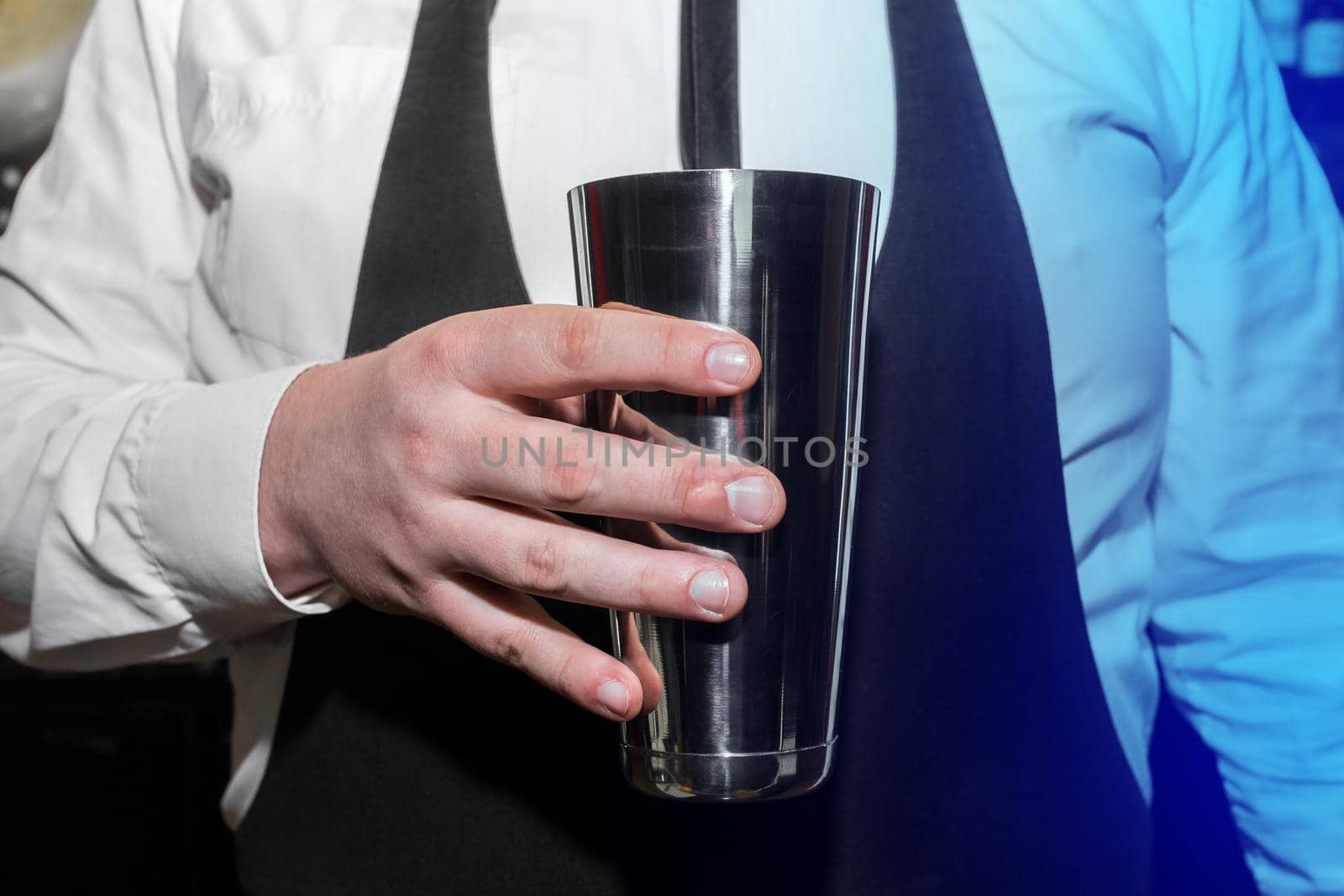 The hand of a professional bartender man holds a tool for mixing and making shaker cocktails.