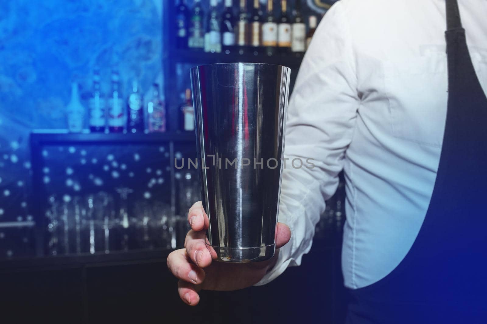 The hand of a professional bartender man holds a tool for mixing and making shaker cocktails.