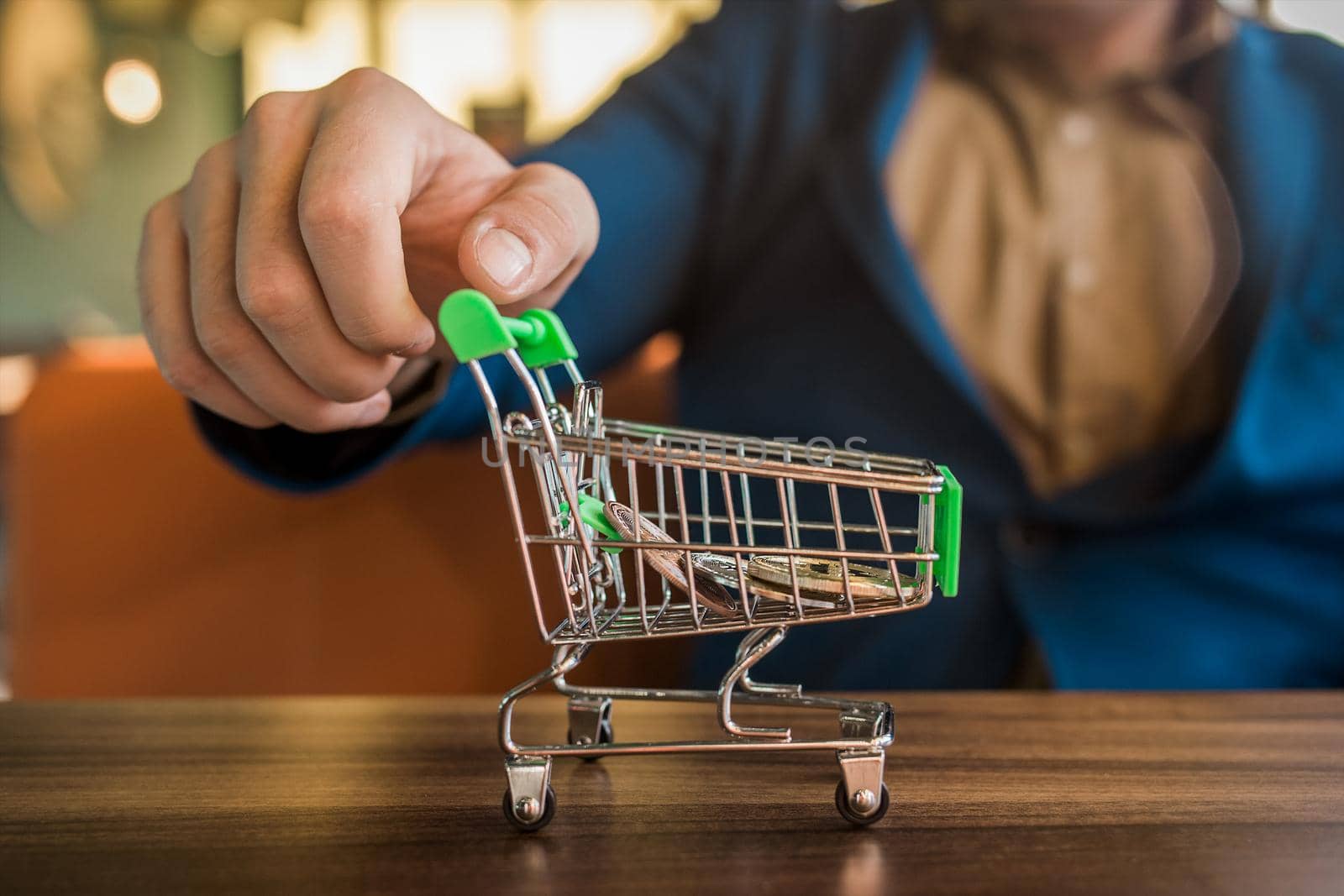 The businessman's hand rolls a shopping cart with bitcoins inside. Cryptocurrency, Business and Modern Currency Finance.
