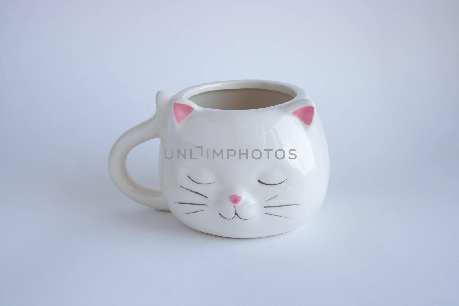 White coffee mug in the shape of a cat with pink ears, close-up on a white background by lapushka62