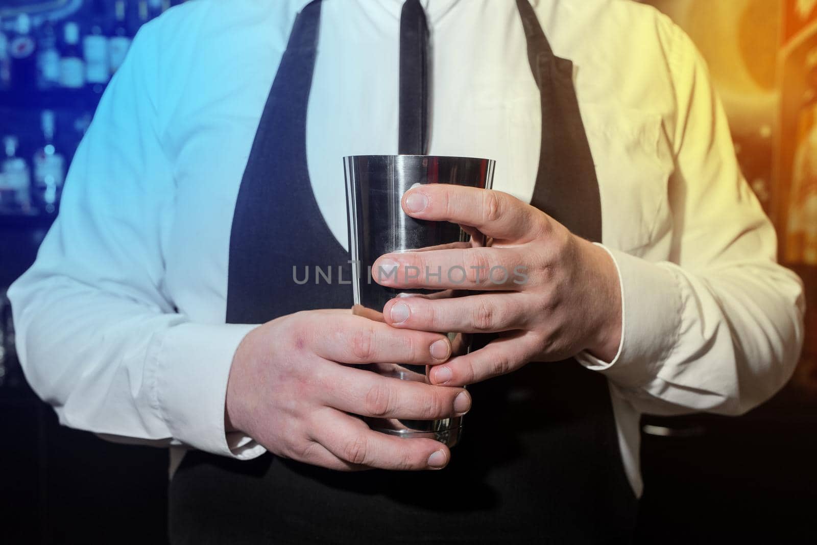 The hands of a professional bartender man holds a tool for mixing and making shaker cocktails by AYDO8