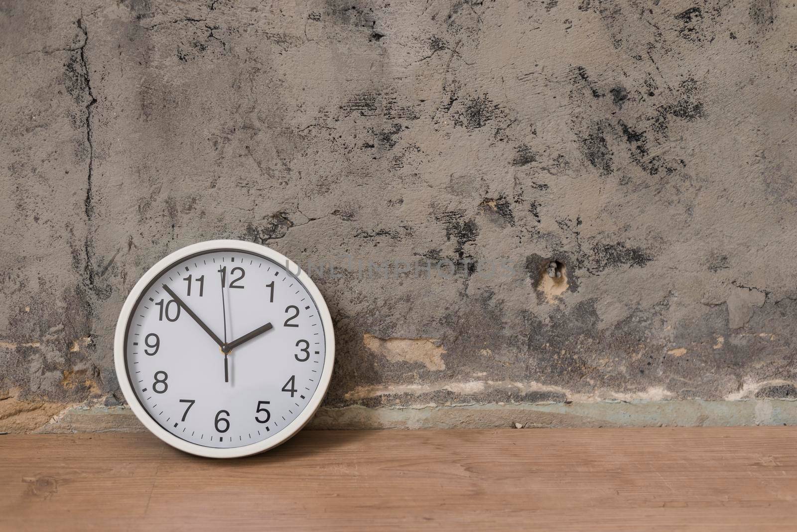 clock wooden desk against weathered wall