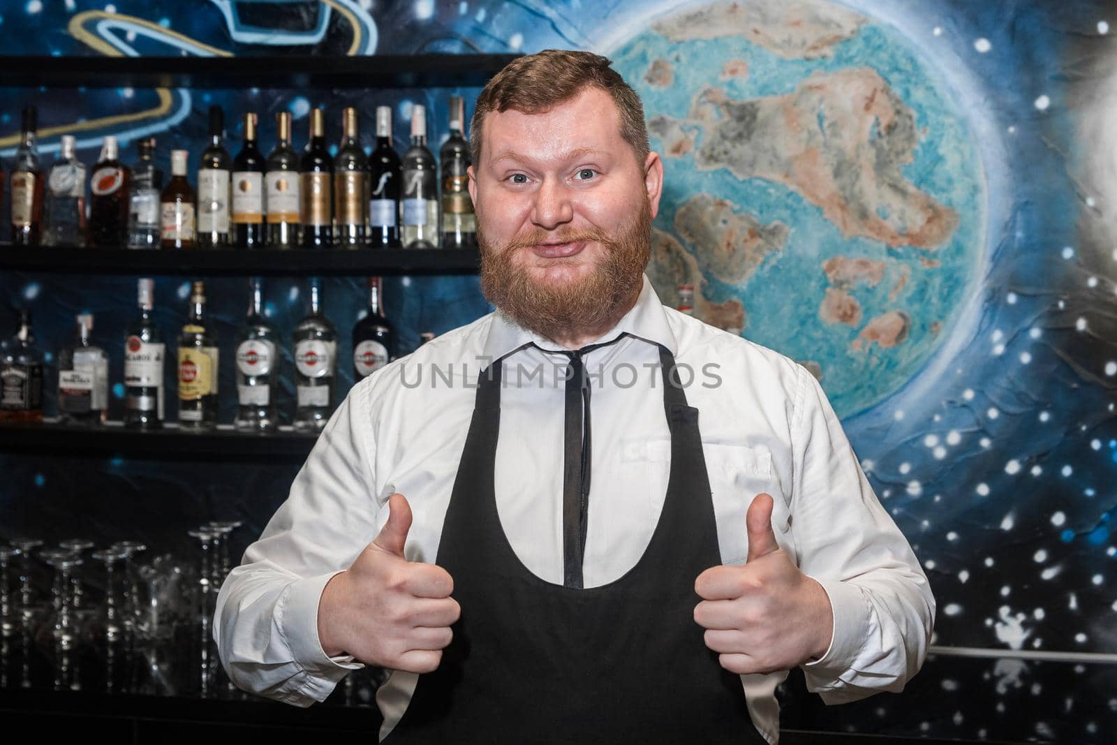 Adult bearded man of European appearance professional bartender shows hand gesture class cool.