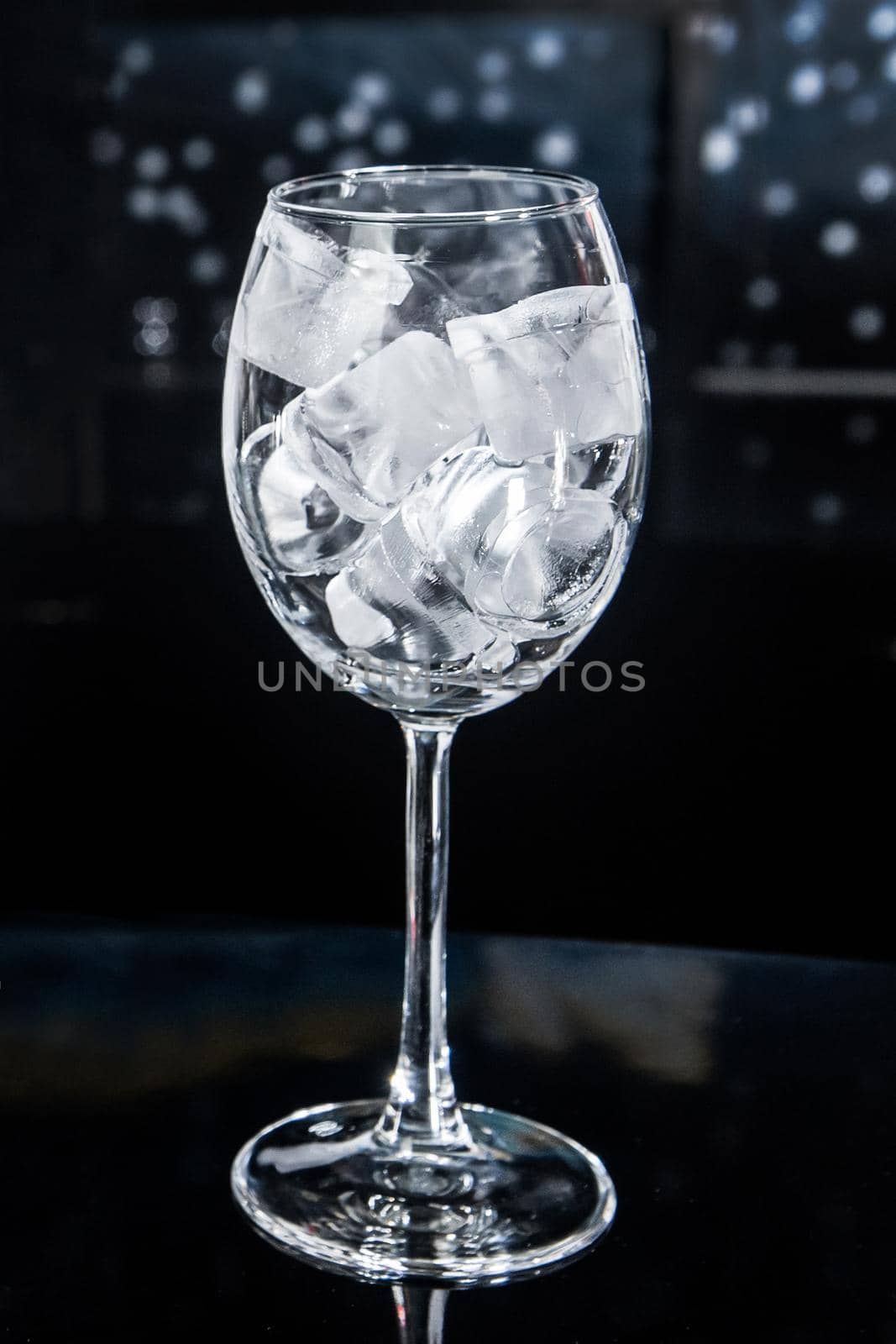 Ice cubes frozen cold ice water liquid white in a glass glass on the bar counter.