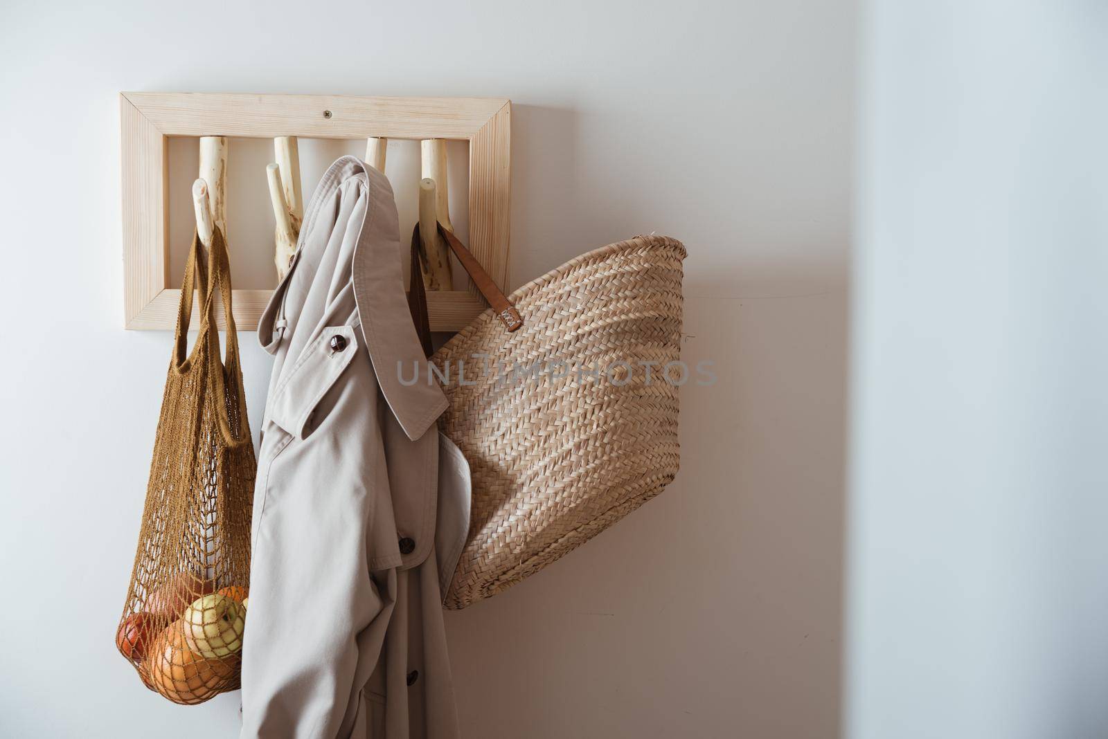 straw bag, mesh bag and trench on handmade wooden hang. Concept of slowlife home. High quality photo