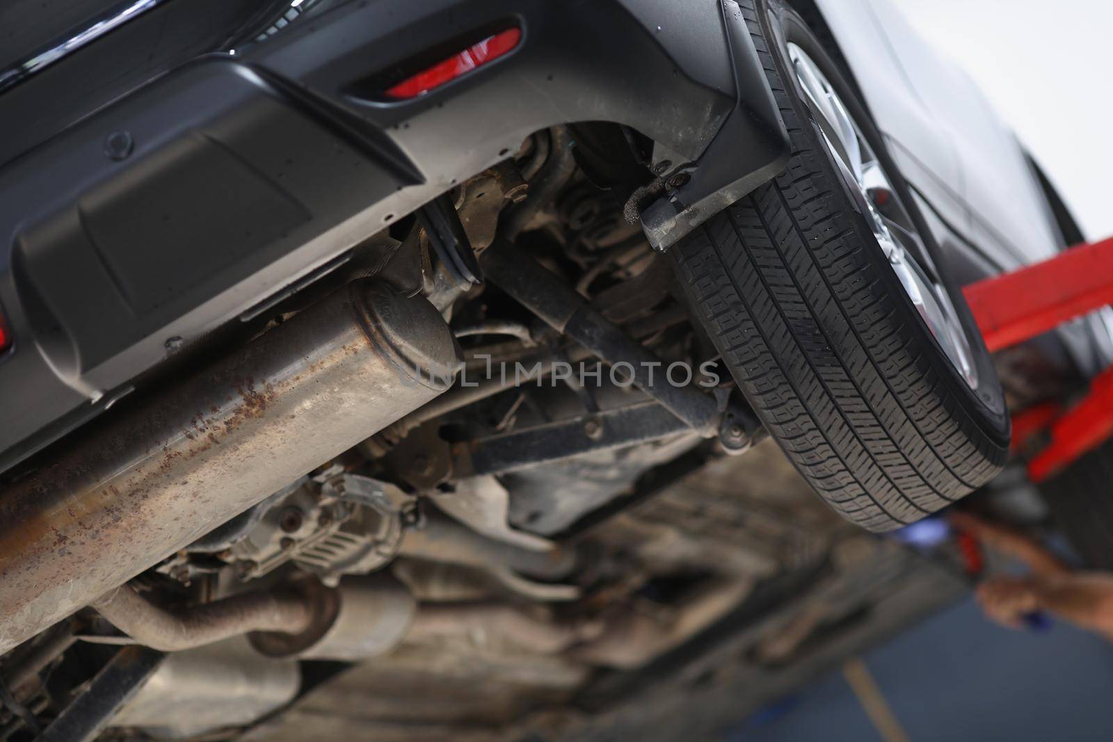 Close-up of car lifted in maintenance service for checkup, undercarriage of automobile, bottom view of elevated machine. Pit stop, car diagnostic concept