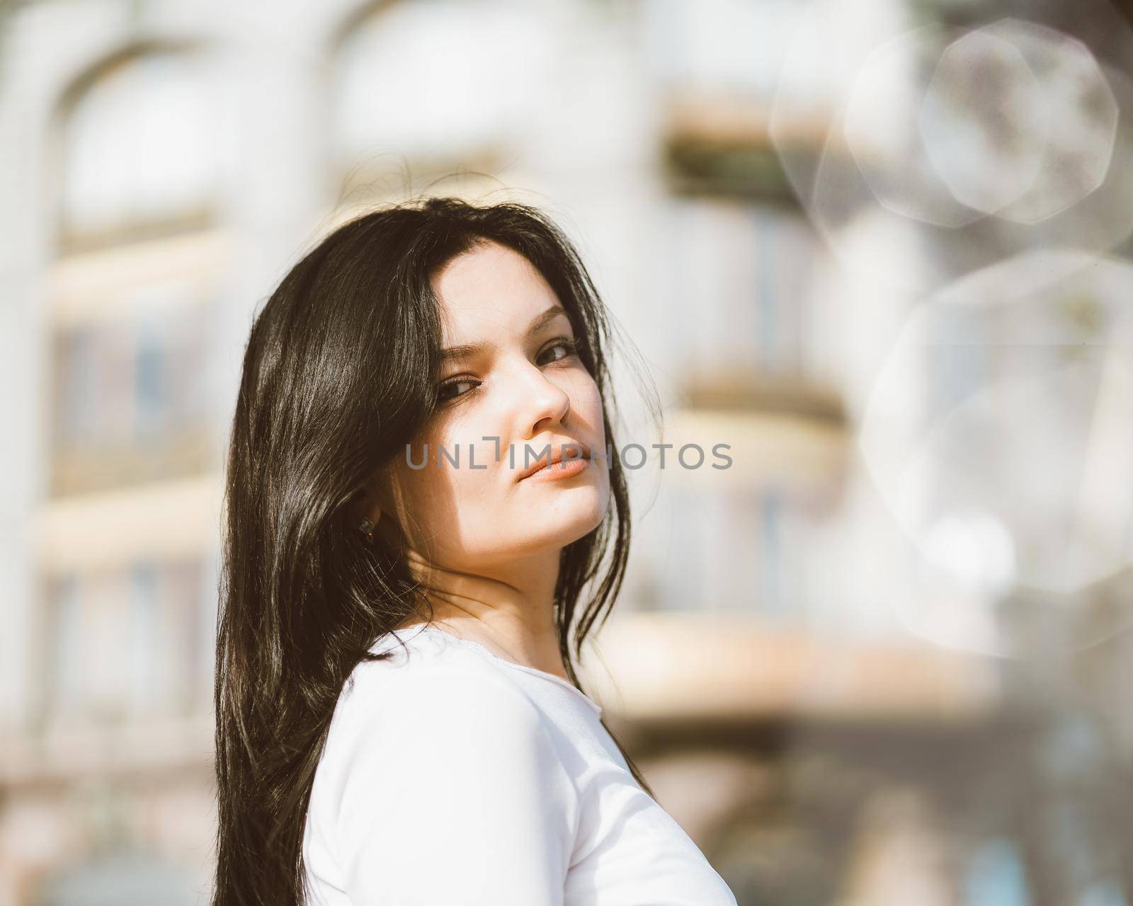 Portrait close-up of beautiful intelligent brunette who walks down street of St. Petersburg in city center. Charming thoughtful woman with long dark hair wanders alone, immersed in thoughts by NataBene