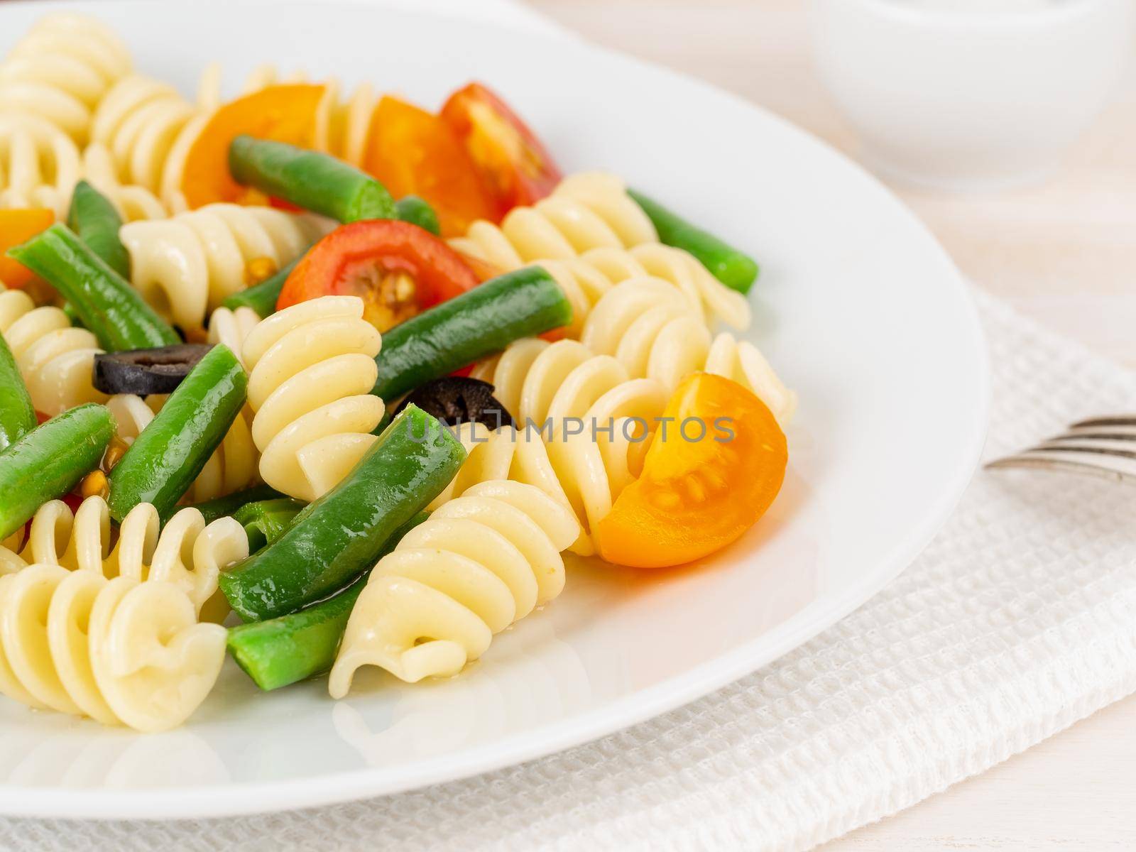 Italian salad with fusilli paste tomatoes, olives, green beans, part of, side view, close up