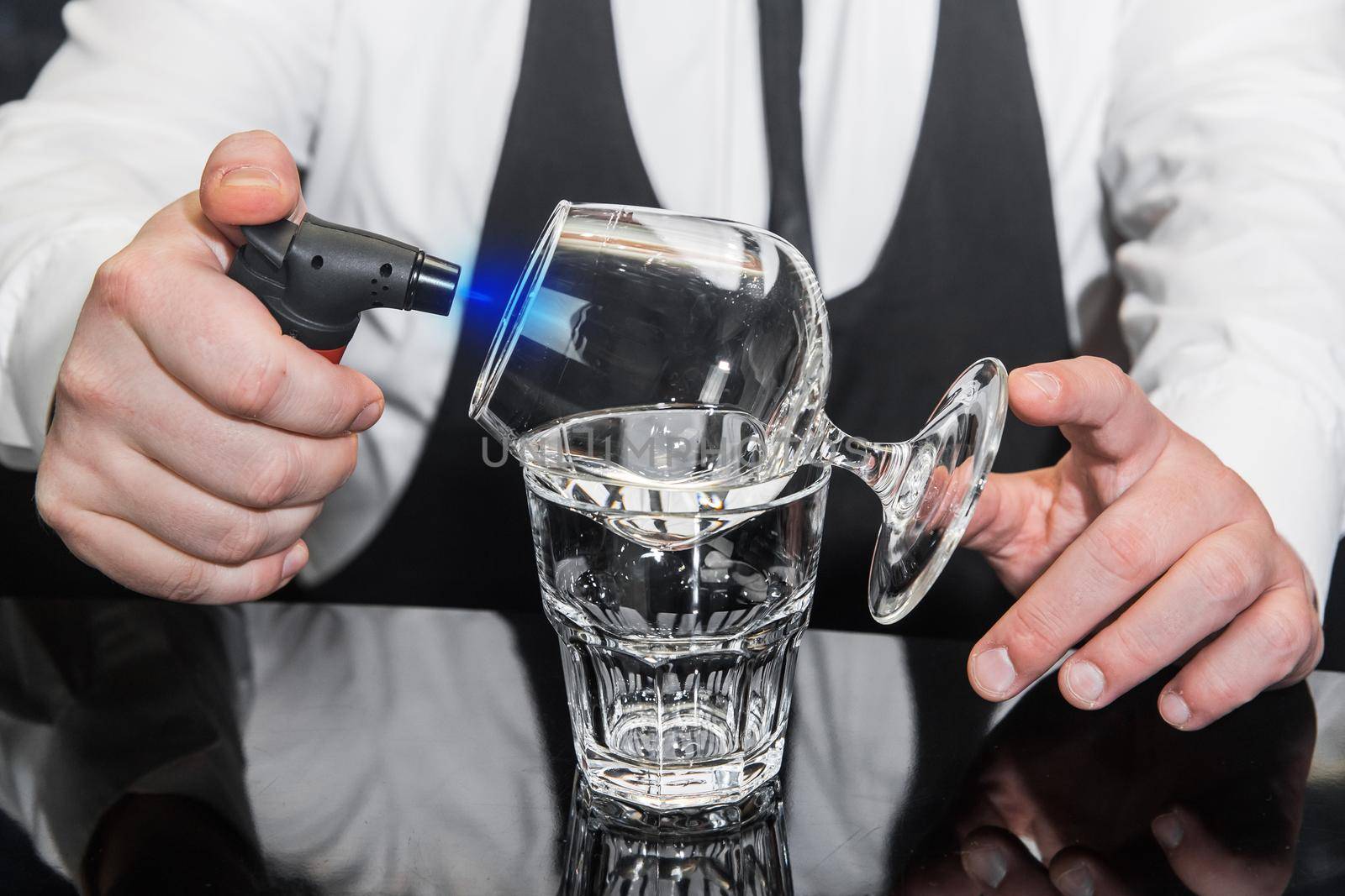 The process of preparing an alcoholic hot cocktail with Italian liqueur of a drink in sambuca glass.