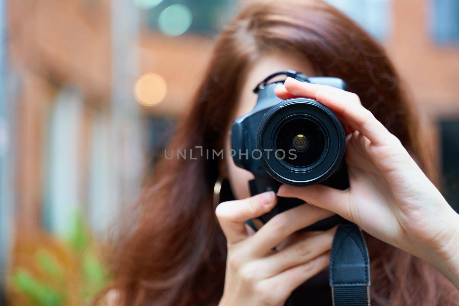 Beautiful stylish fashionable girl holds a camera in her hands and takes pictures. Woman photographer with long dark hair, copy space